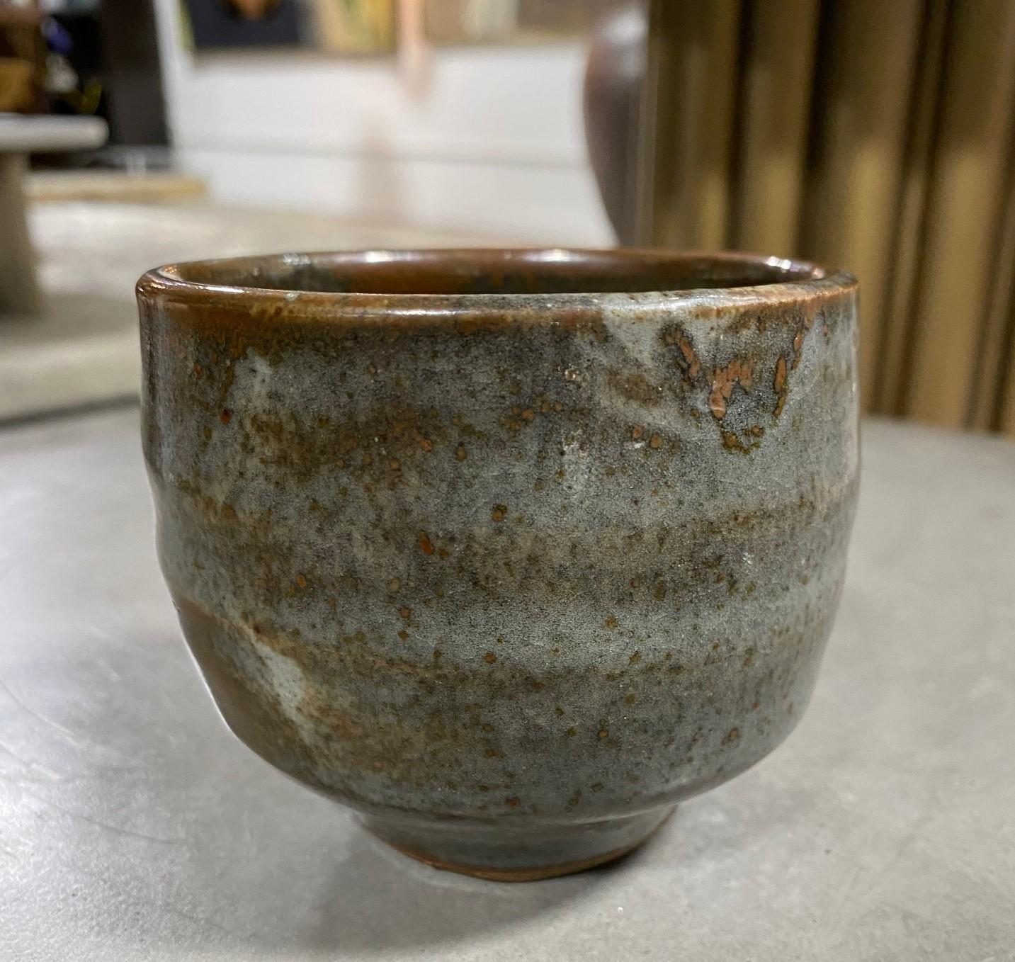 A beautiful Japanese yunomi teacup featuring a muted green glaze with a white overlay and subtle shifts in color and texture. The work glows in the light. 

This little gem came from a collector of fine Japanese and Asian ceramics - a collection