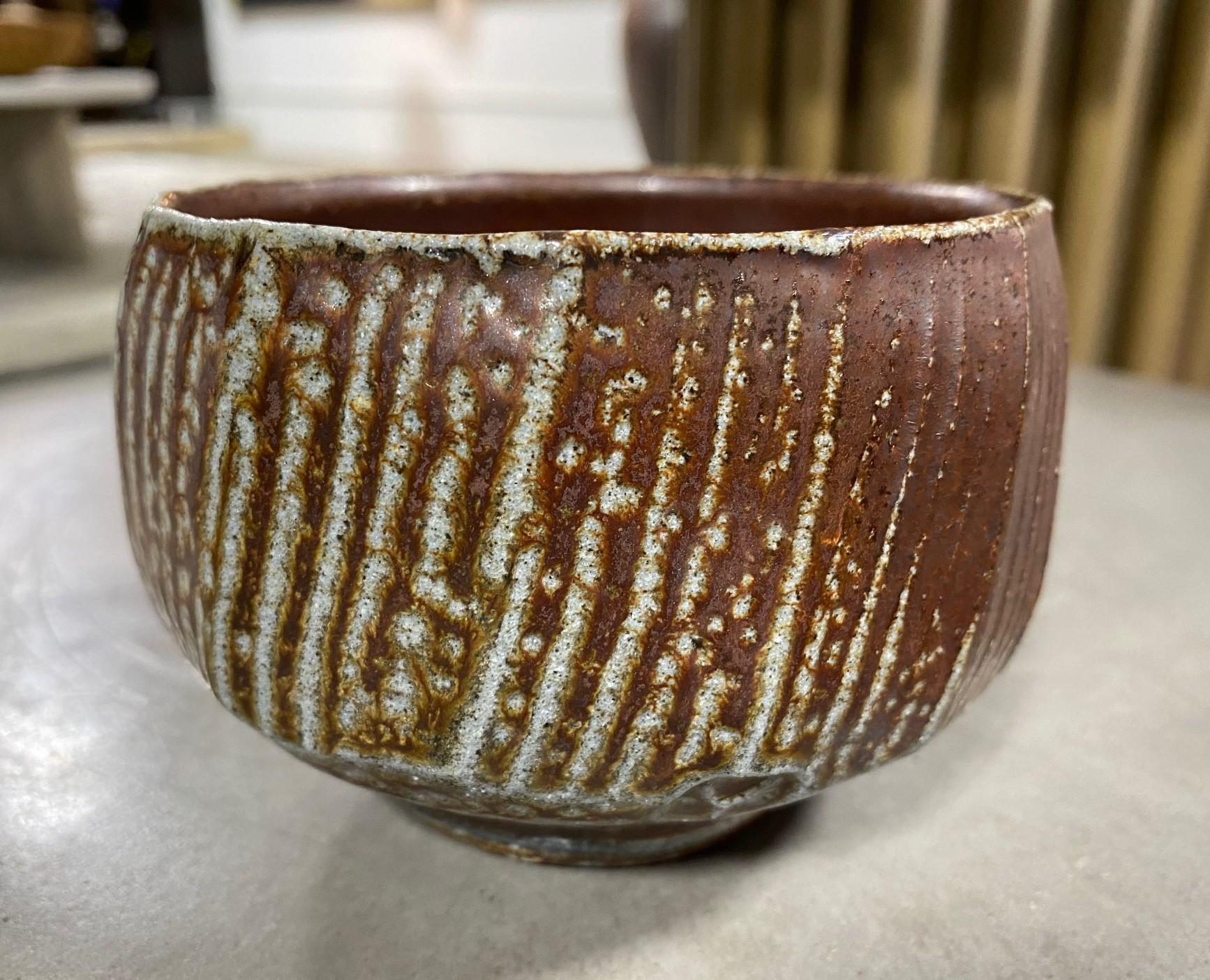 A stunning Japanese stoneware Studio Pottery chawan tea bowl that features a beautiful dark rich glaze with wonderful shifts in pattern and texture. 

This particular piece encompasses the Japanese Wabi-Sabi aesthetic (which is so revered and