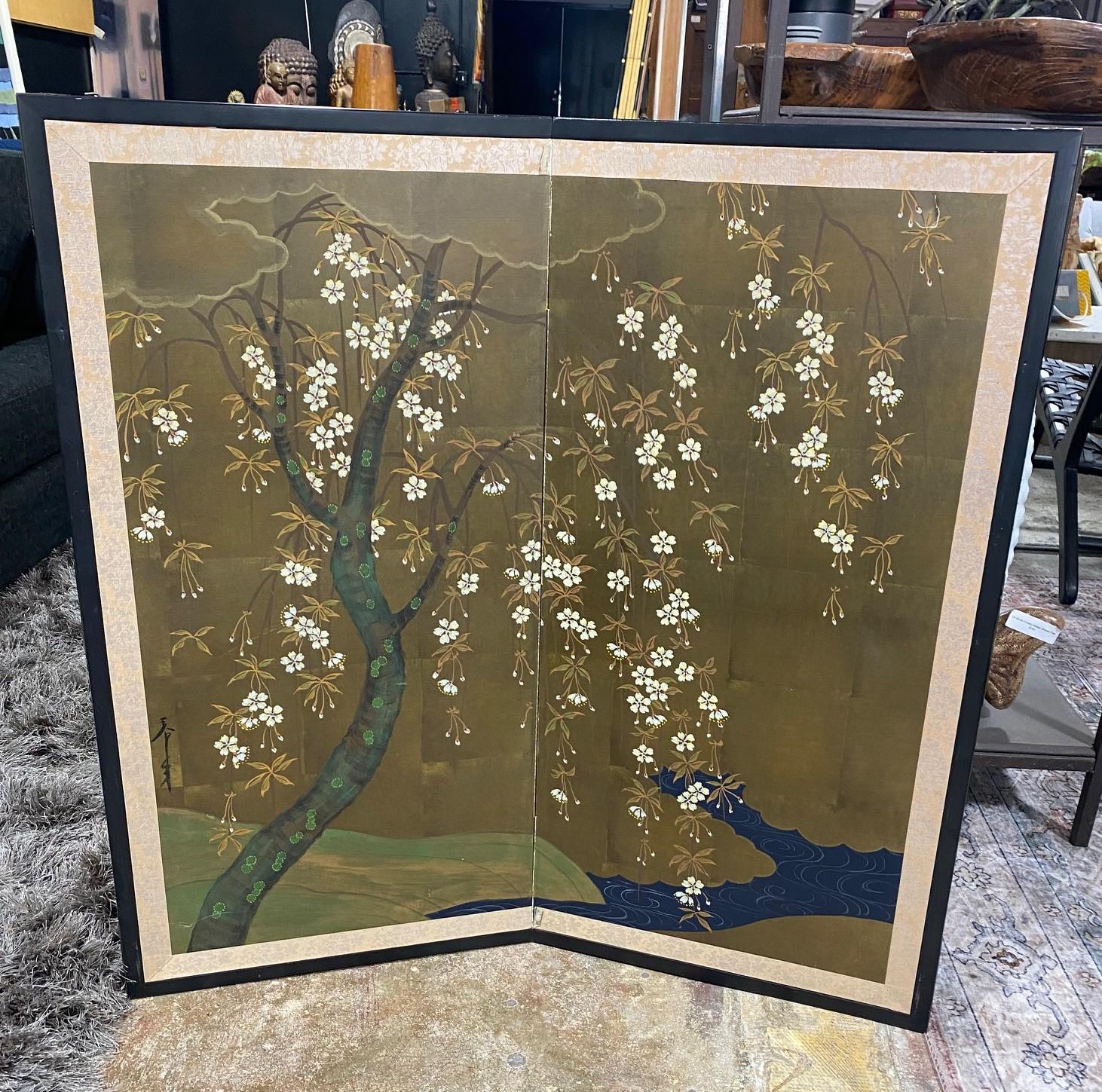A gorgeous two-panel Japanese Byobu folding screen depicting a nature landscape scene with a blossoming flower tree and a running stream below. The bright, rich colors, gold leaf, and beautiful hand-painted detail of the tree's trunk, branches and