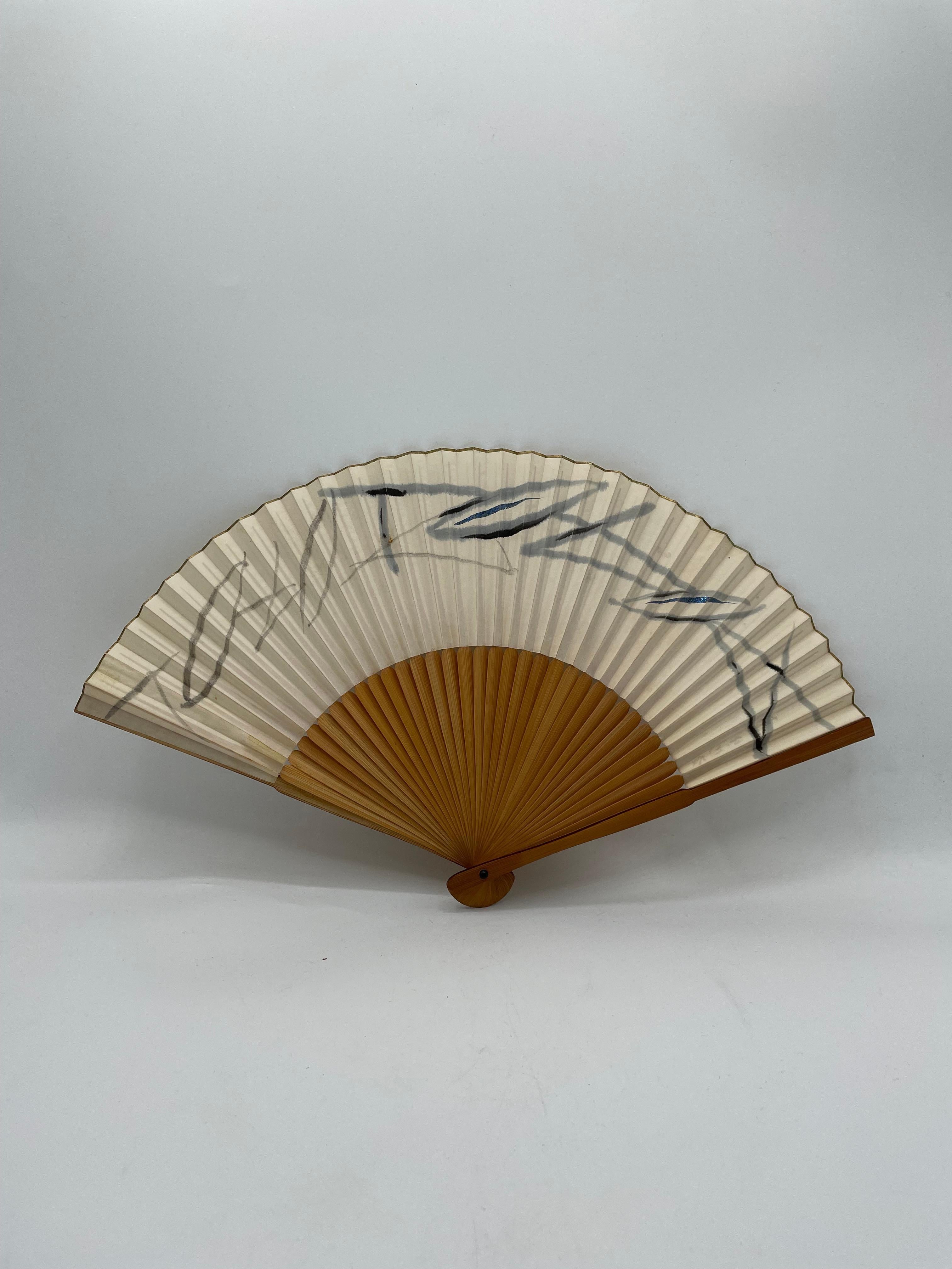 This is a fan which was made in Japan around 1980s in Showa era.
This is made with a paper and bamboos. 

This fan has a lot of stains. 

Japanese fans are made of paper on a bamboo frame, usually with a design painted on them. In addition to