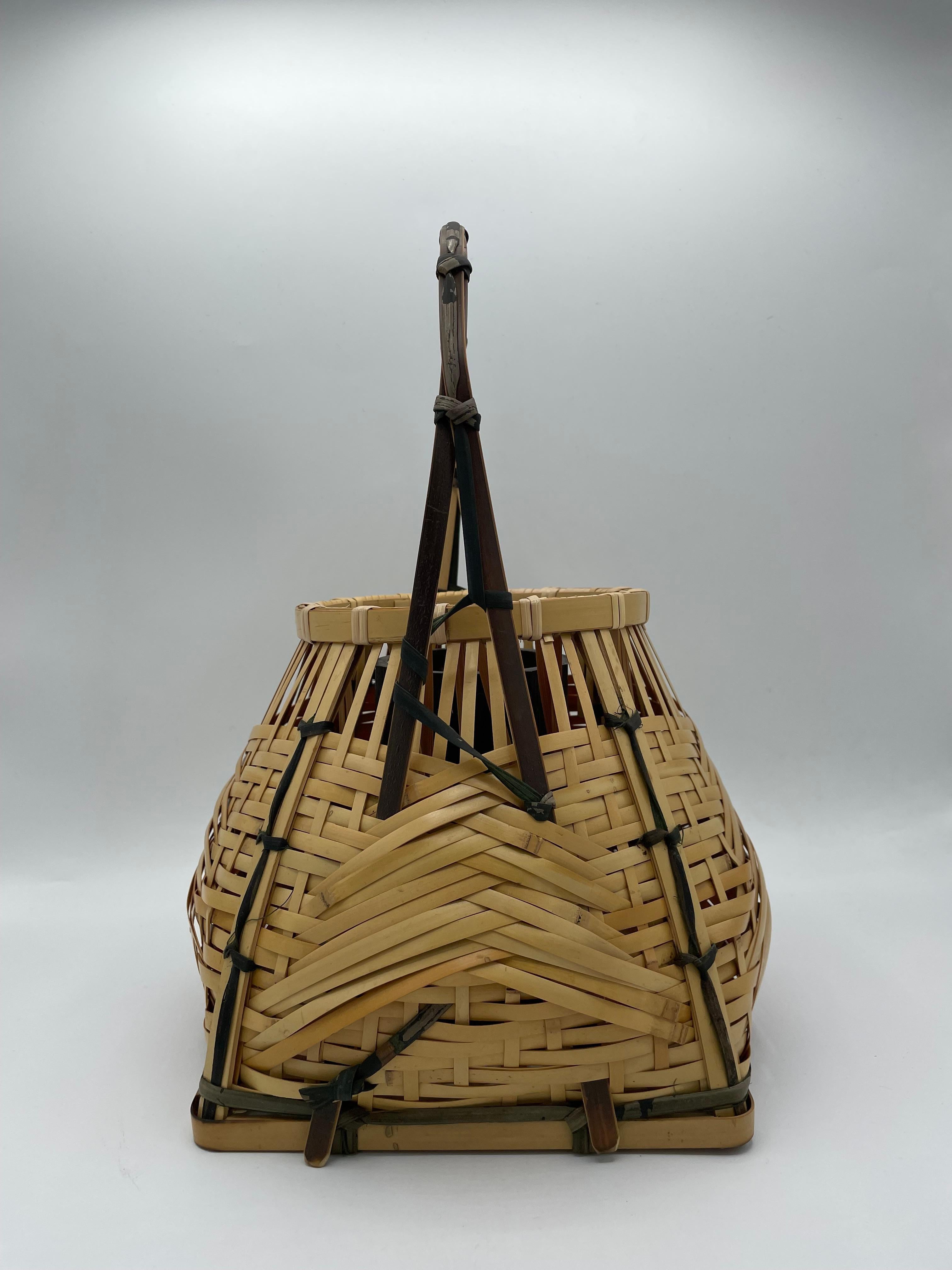 This is a bamboo basket called 'Souzen kago'.
Souzen kago was liked by Souzen HISADA. It is famous by the shape, the bottom is a rectangle and the top is a circle shape. 
This basket was made by Chikusei. 

It was used to use for the tea ceremony.