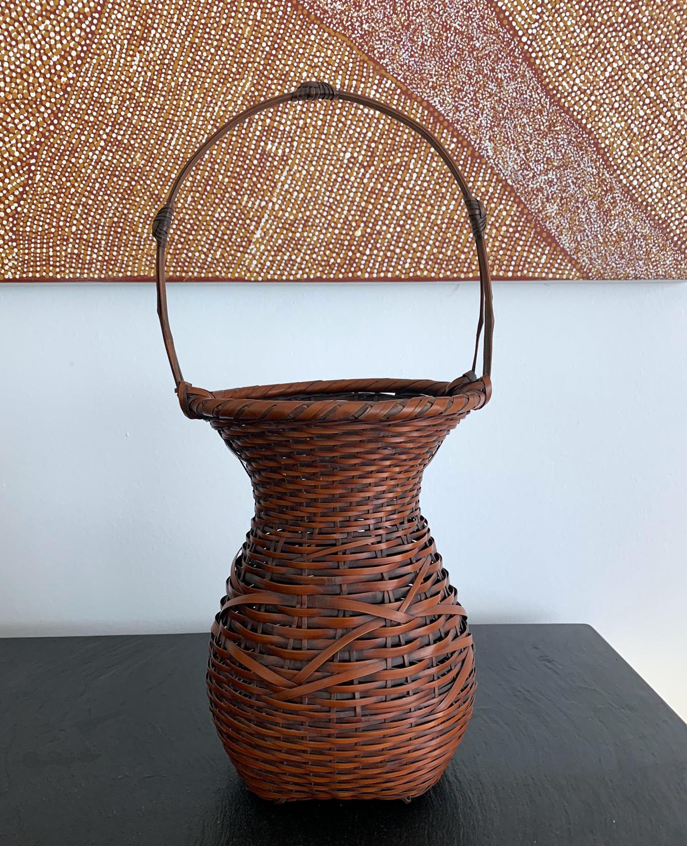 A handwoven bamboo basket used as an ikebana by Japanese Bamboo artist Yufu Shohaku (b. 1941-). The basket was constructed using different sizes of pine needle plaiting intercepted with irregular plaiting. The feet were finished in a subtle looped