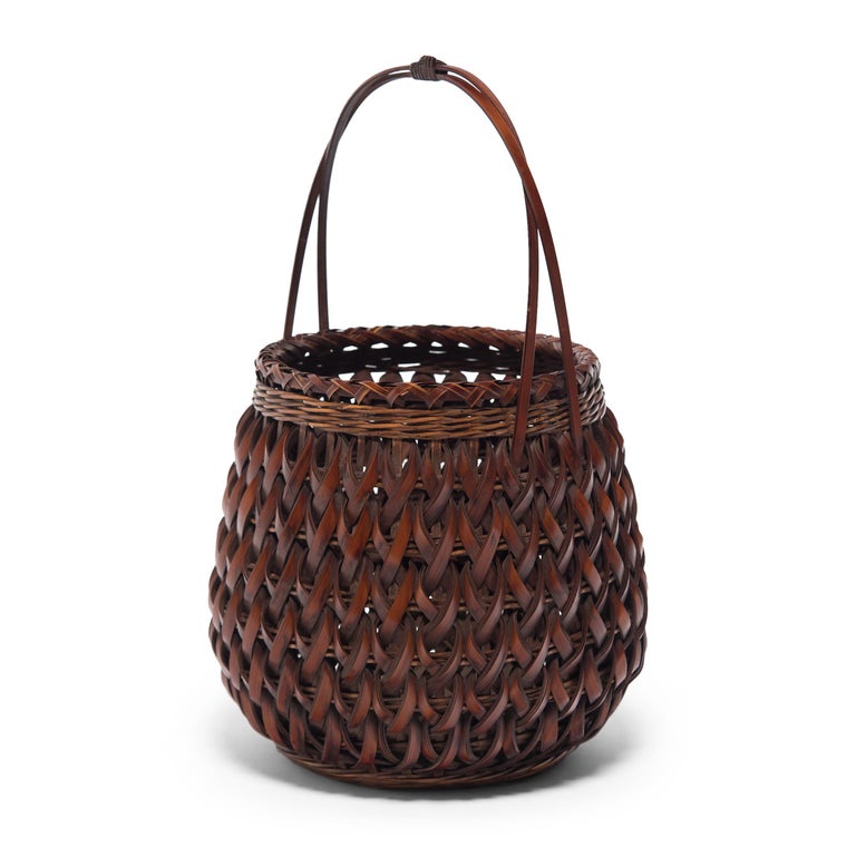 This one of a kind bamboo basket is a late-Meiji era flower basket (hanakago) designed especially for ikebana, the Japanese art of floral arrangement. Woven of smoked bamboo (susutake), the basket has a rounded, barrel form surmounted by a high,