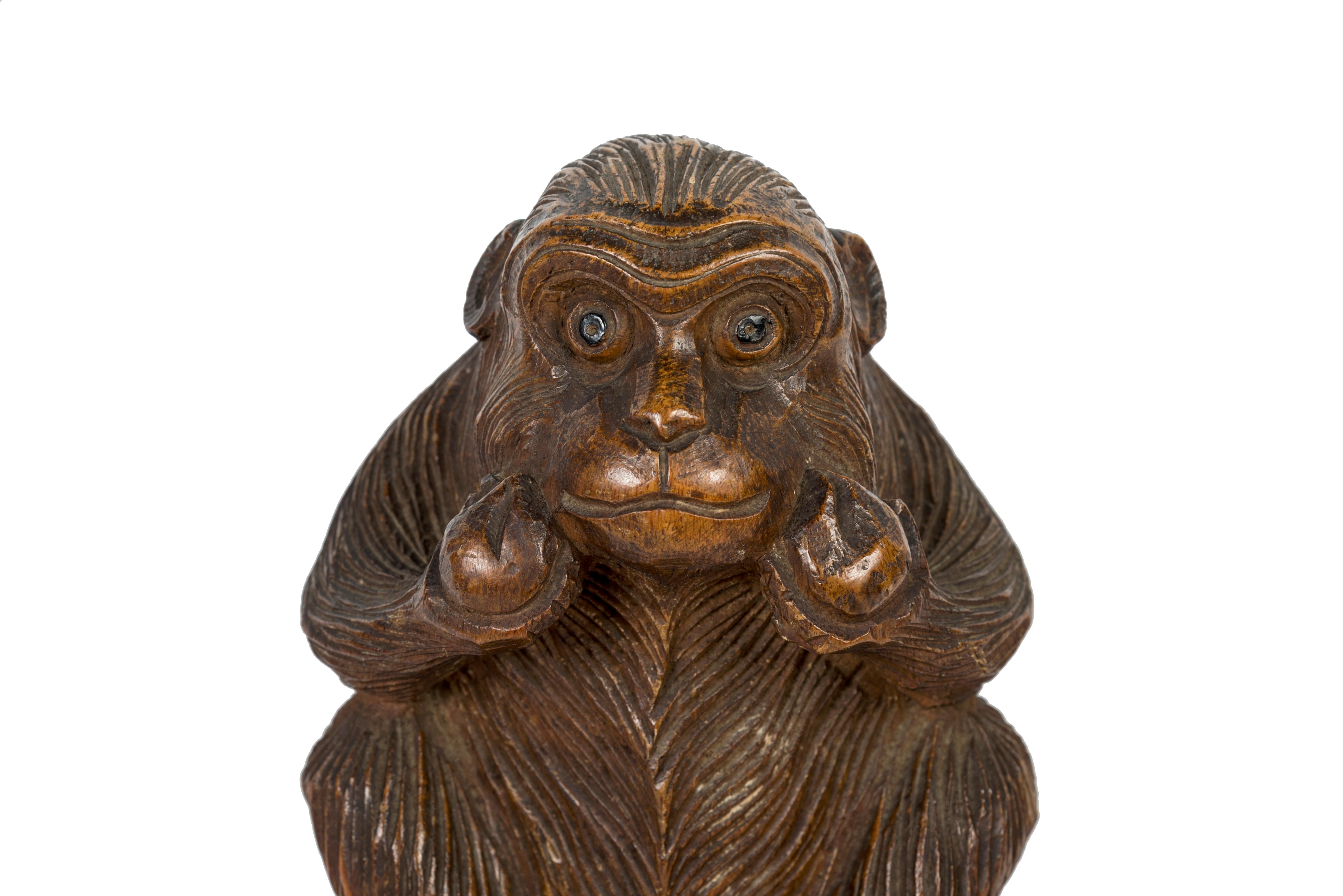 Sculpture en bois ciselé représentant un singe assis tenant dans ses mains des pêches de longévité. L'impression de la fourrure est très réaliste, et ses yeux sont rehaussés de laque noire.
La figure du singe avec des pêches de longévité est une