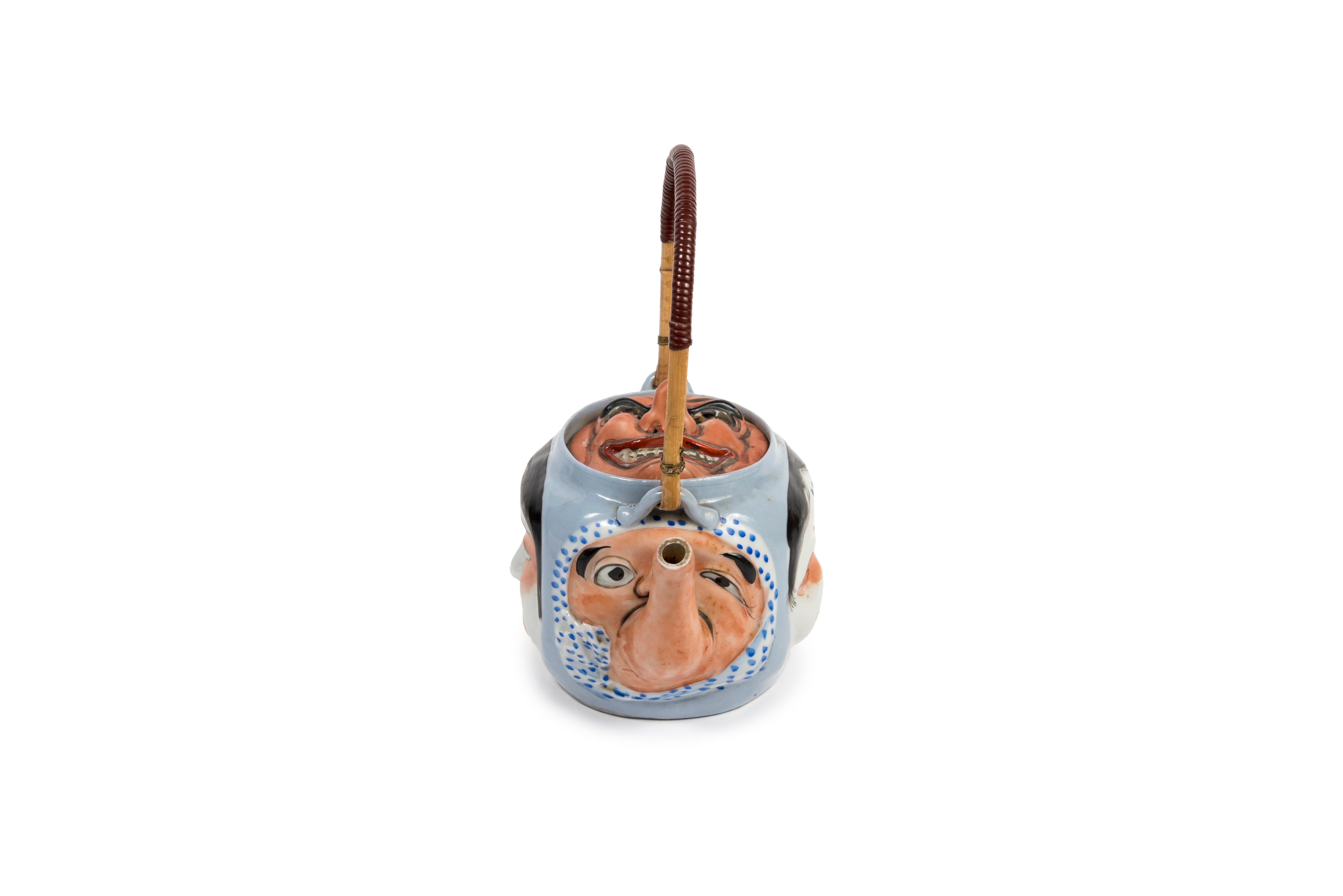 Banko polychrome enamelled terracotta teapot, representing on each side masks from the Japanese folklore. Handle in wickerwork.

On the spout, Hyottoko, a comical and childlike character. He is recognizable by the shape of his elongated mouth with