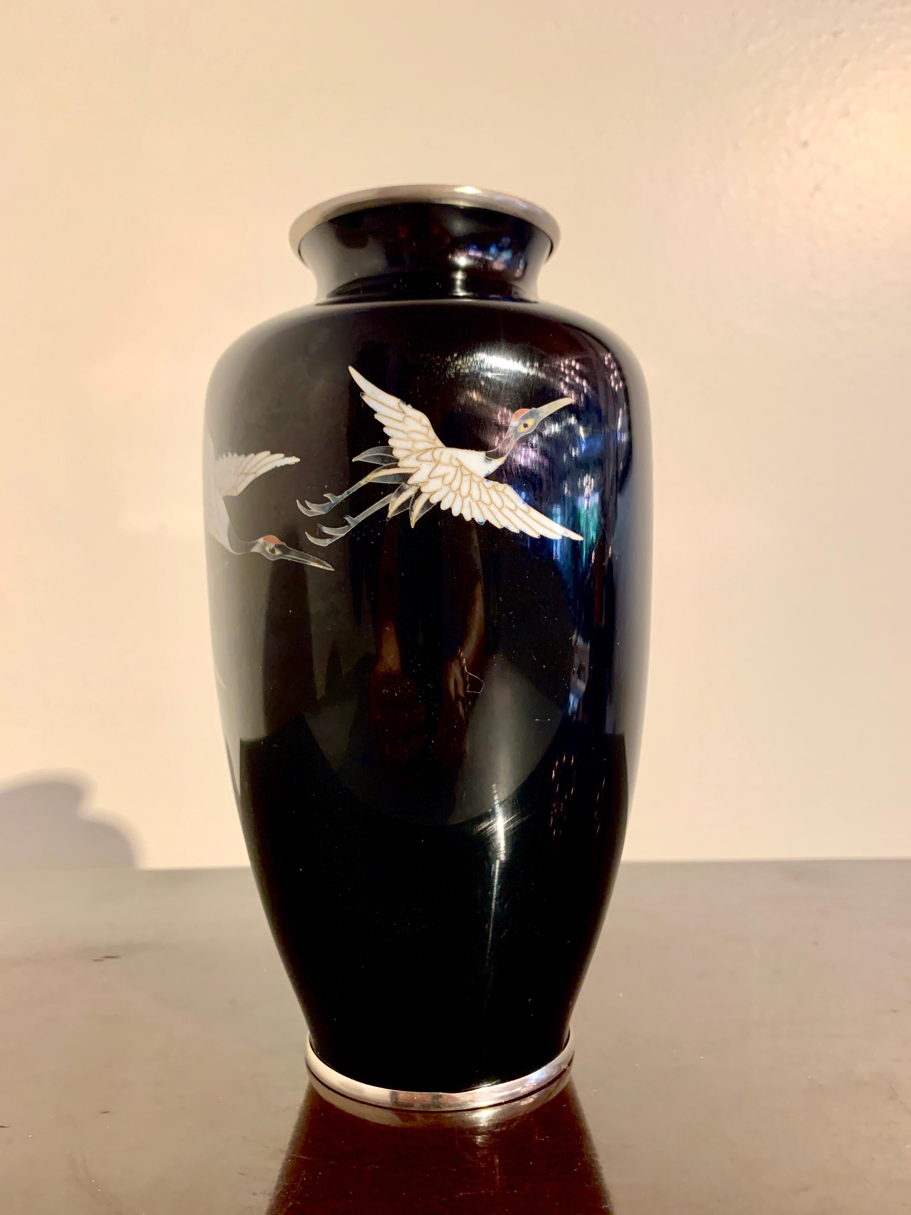 A nice Japanese mirror black cloisonné vase with cranes in flight, by the Sato Cloisonne Company, Showa Period, mid 20th century, Japan.

The vase of baluster form, with an ovoid body, high shoulders, short neck, and slightly everted mouth. 
The