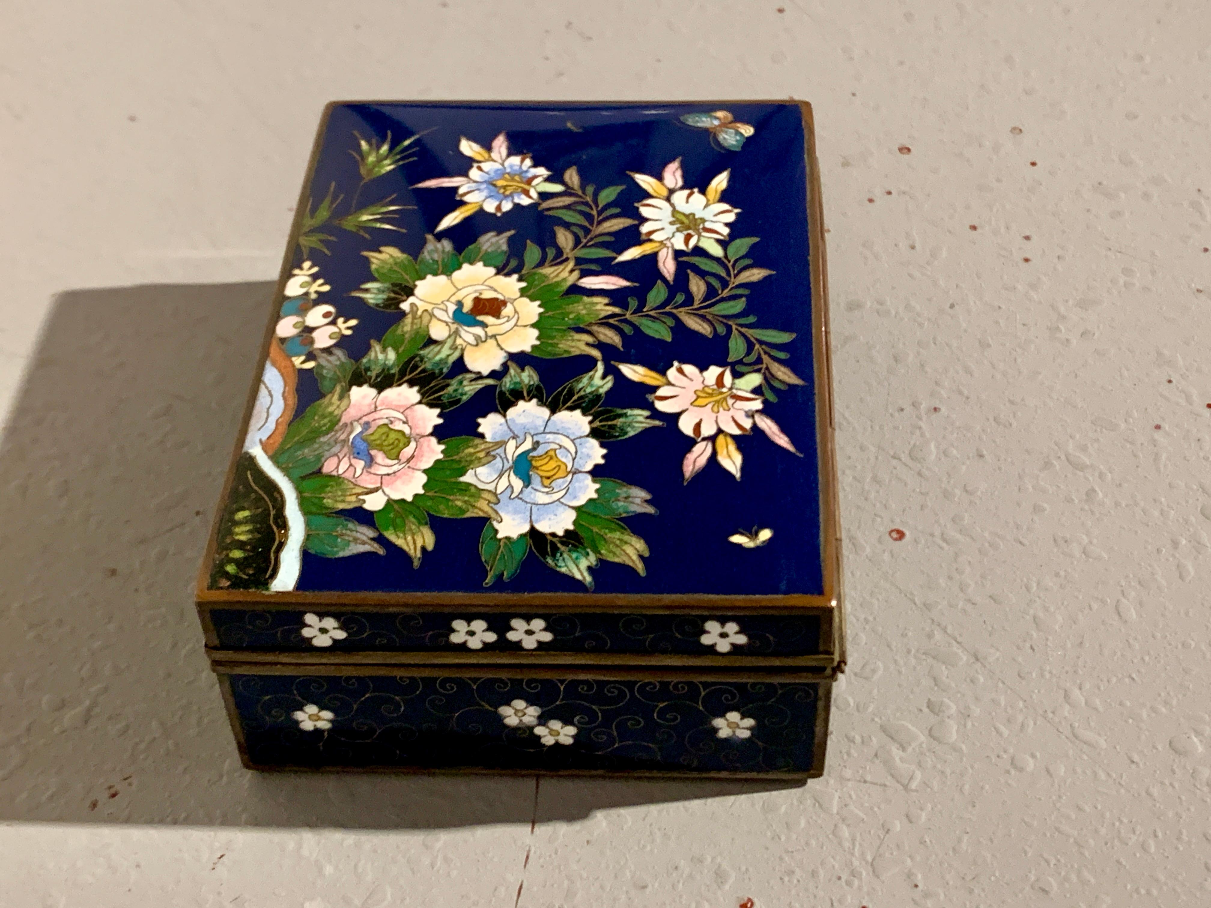 A beautifully decorated deep blue cloisonne hinged top box, Meiji period, circa 1910, Japan.

The trinket or jewelry box featuring a slightly domed lid decorated with a bold design of blossoming peony and lily in muted shades of pink, blue and