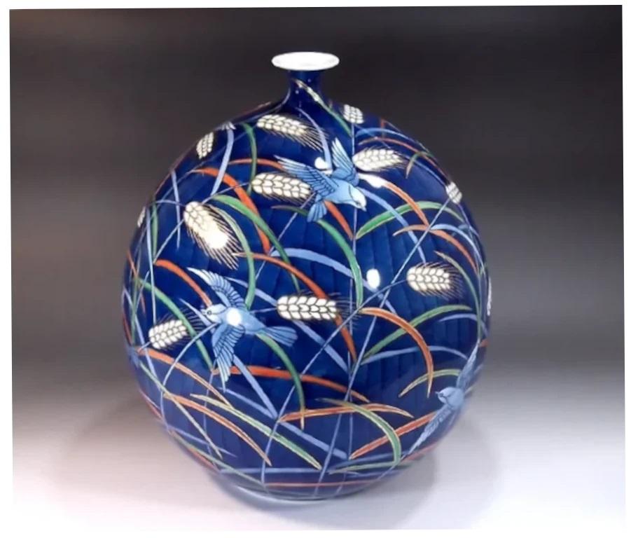 Exquisito jarrón decorativo de porcelana japonesa contemporánea, pintado a mano de forma extremadamente intrincada en blanco, rojo y azul bajo vidriado sobre un fondo azul cobalto, sobre un hermoso cuerpo de forma ovoide, una pieza firmada por el