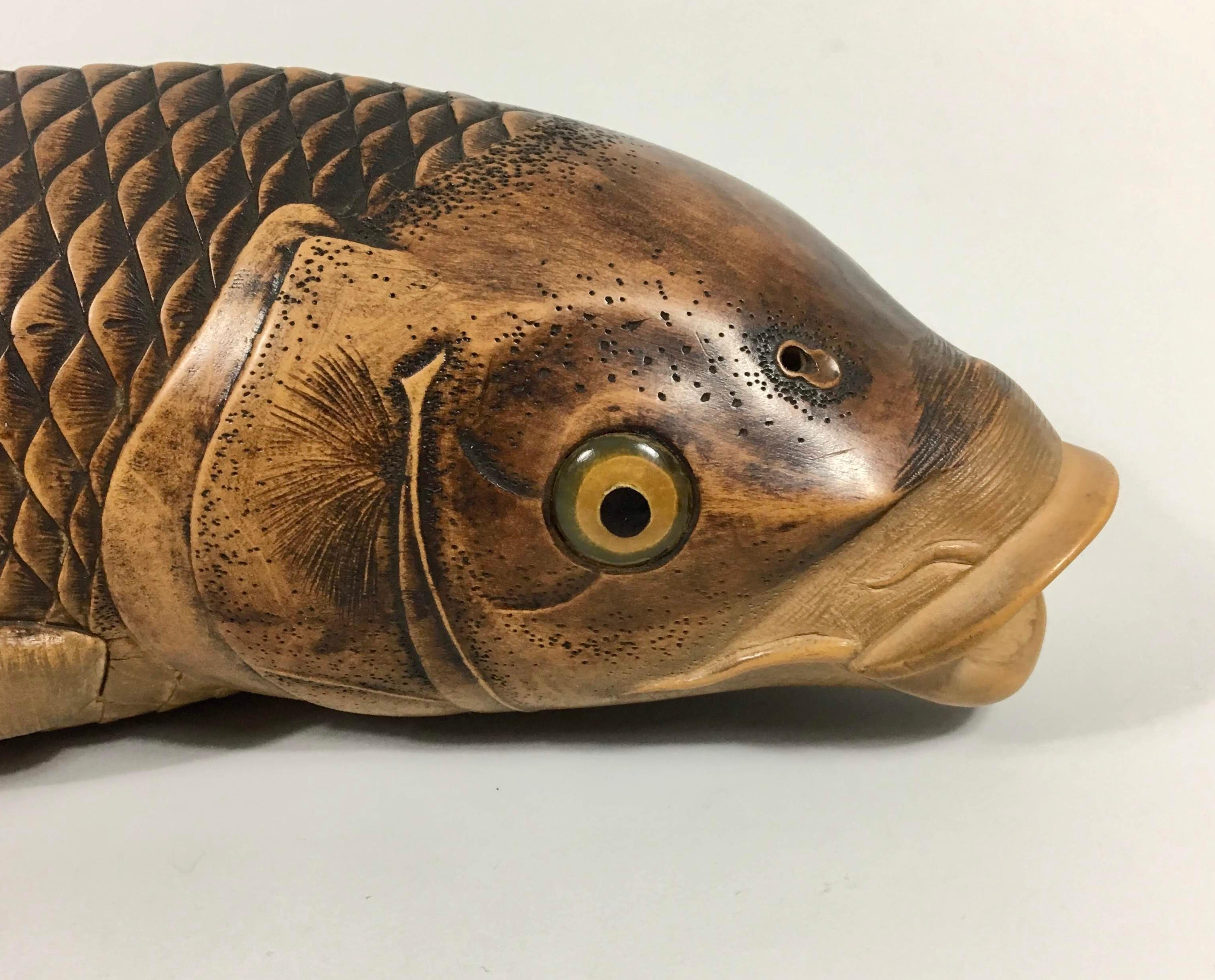 A fine and large carved wood okimono, by Nishikawa Suketsugu, Meiji Period (1868-1912). Beautifully and naturistically carved as a large carp, it’s body curved slightly to the left, pushing through an imaginary current. Rendered with detailed