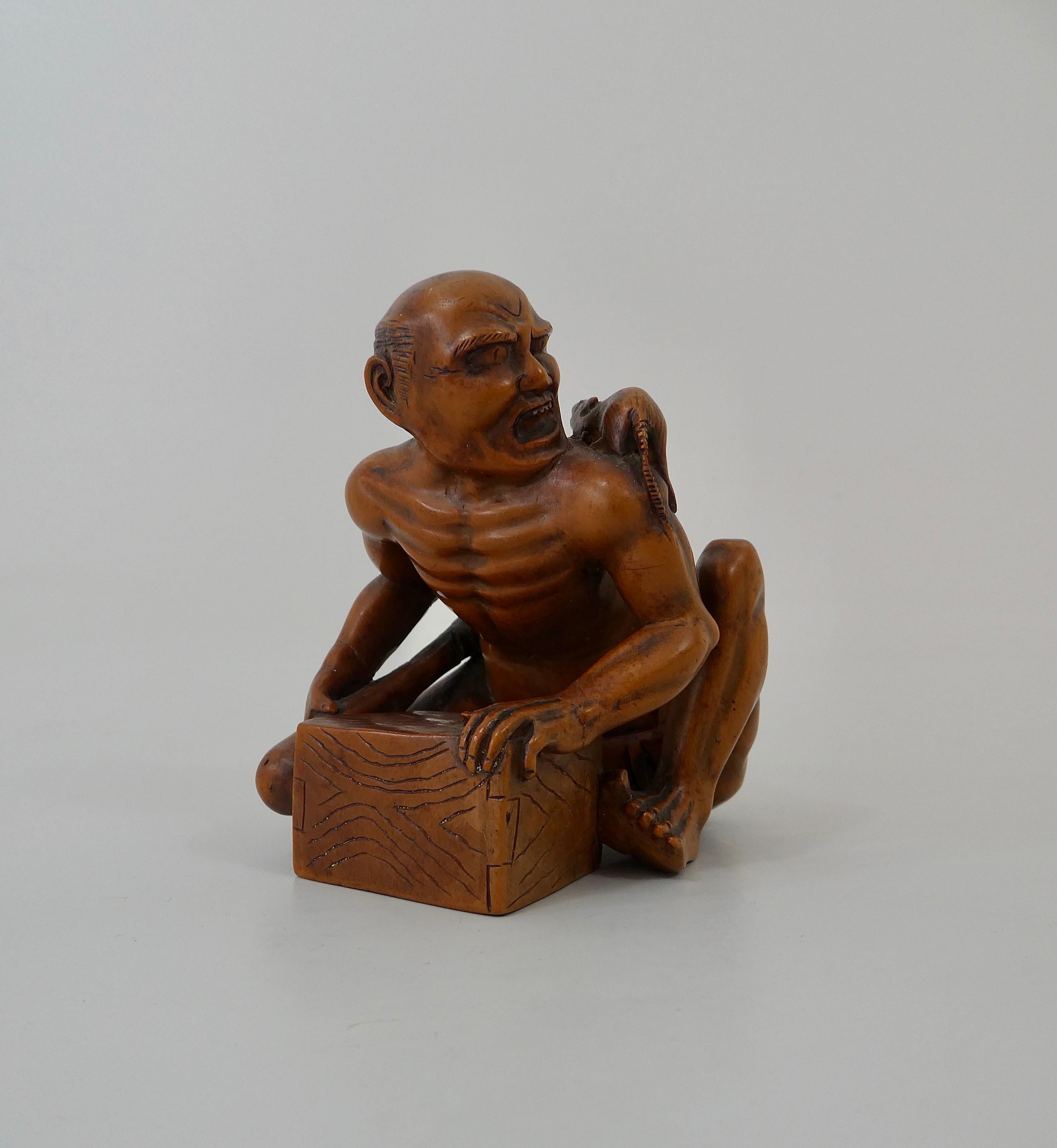Japanese boxwood okimono, Meiji period (1868-1912). Well carved as ‘The Rat Catcher. The catcher crouched over his box, holding a club in his right hand, whilst having a look of horror on his face, as realizes that the large rat is running over his