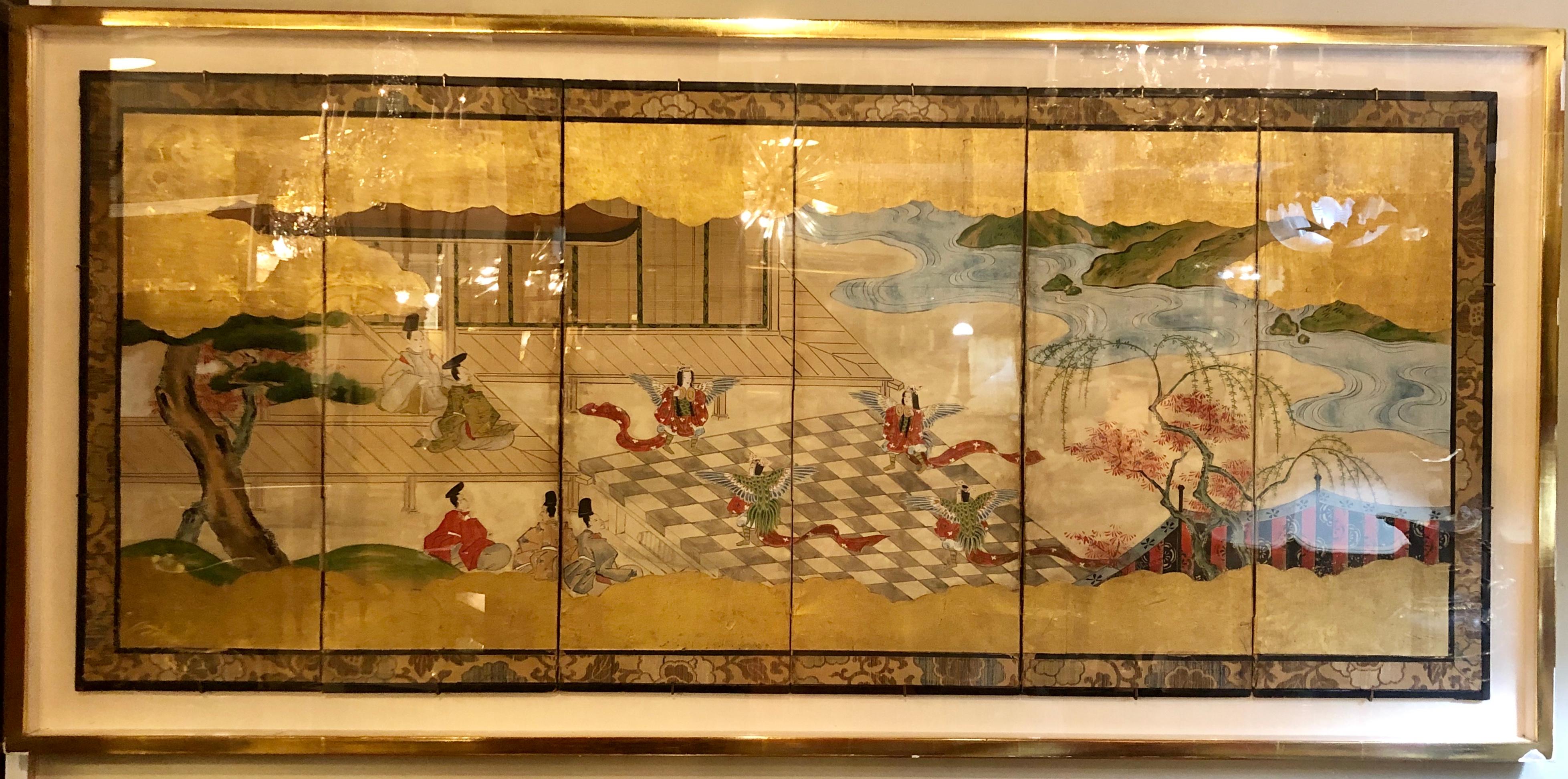 Japanese brilliant silk gilt screen six-panel under glass, superior details abound in this one of a kind silk screen having six panels telling a story as elders sit and watch winged female dancers in the garden. The whole under glass in a finely