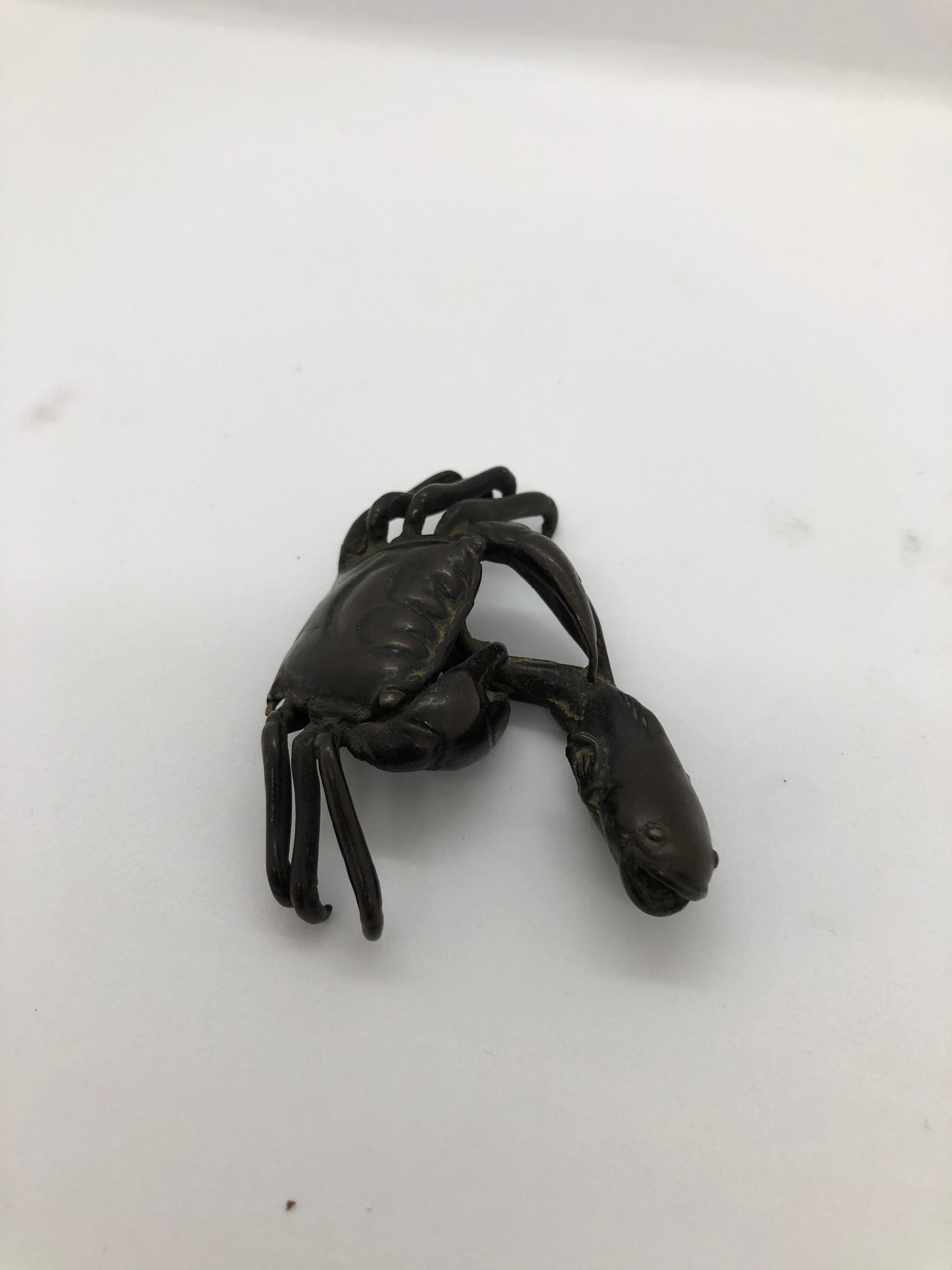 A small bronce sculpture depicting a crab catching a fish. Japanese, late 19th century.