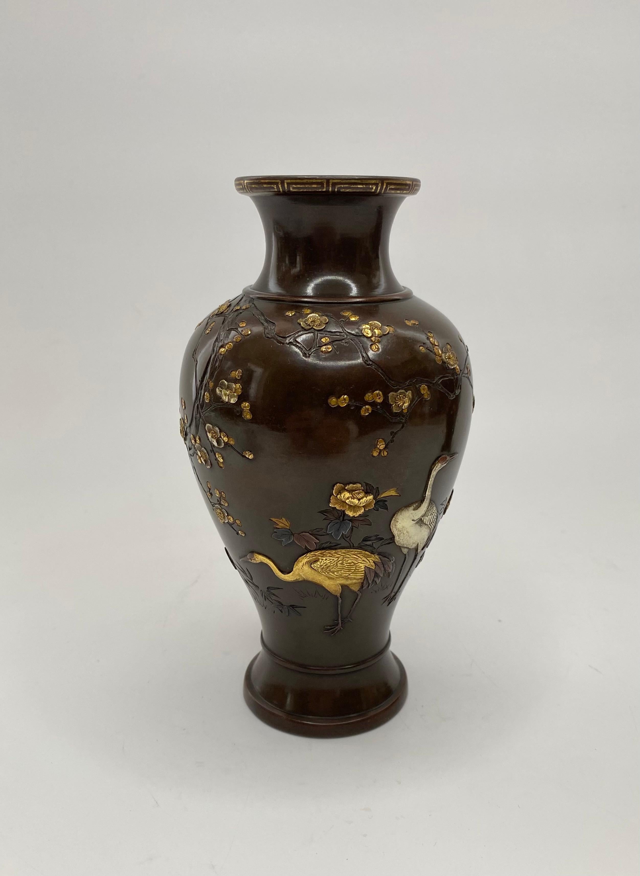 A fine pair of Japanese bronze and mixed metal vases, by Inoue of Kyoto, Meiji Period. The baluster shaped vases, decorated in gold, silver and shakudo inlay, with cranes beneath flowering cherry blossom trees, with insects flying above. The details