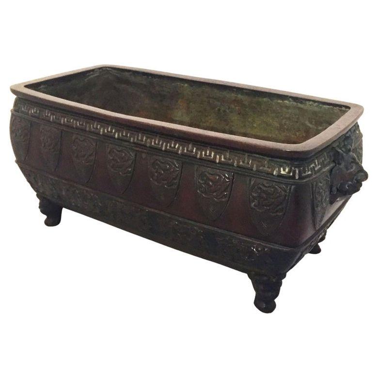 A fine large Japanese bronze rectangular bonsai pot or planter urn from the Meiji Period, featuring taotie ogre face mask handles and stylized phoenix designs around the circumference.