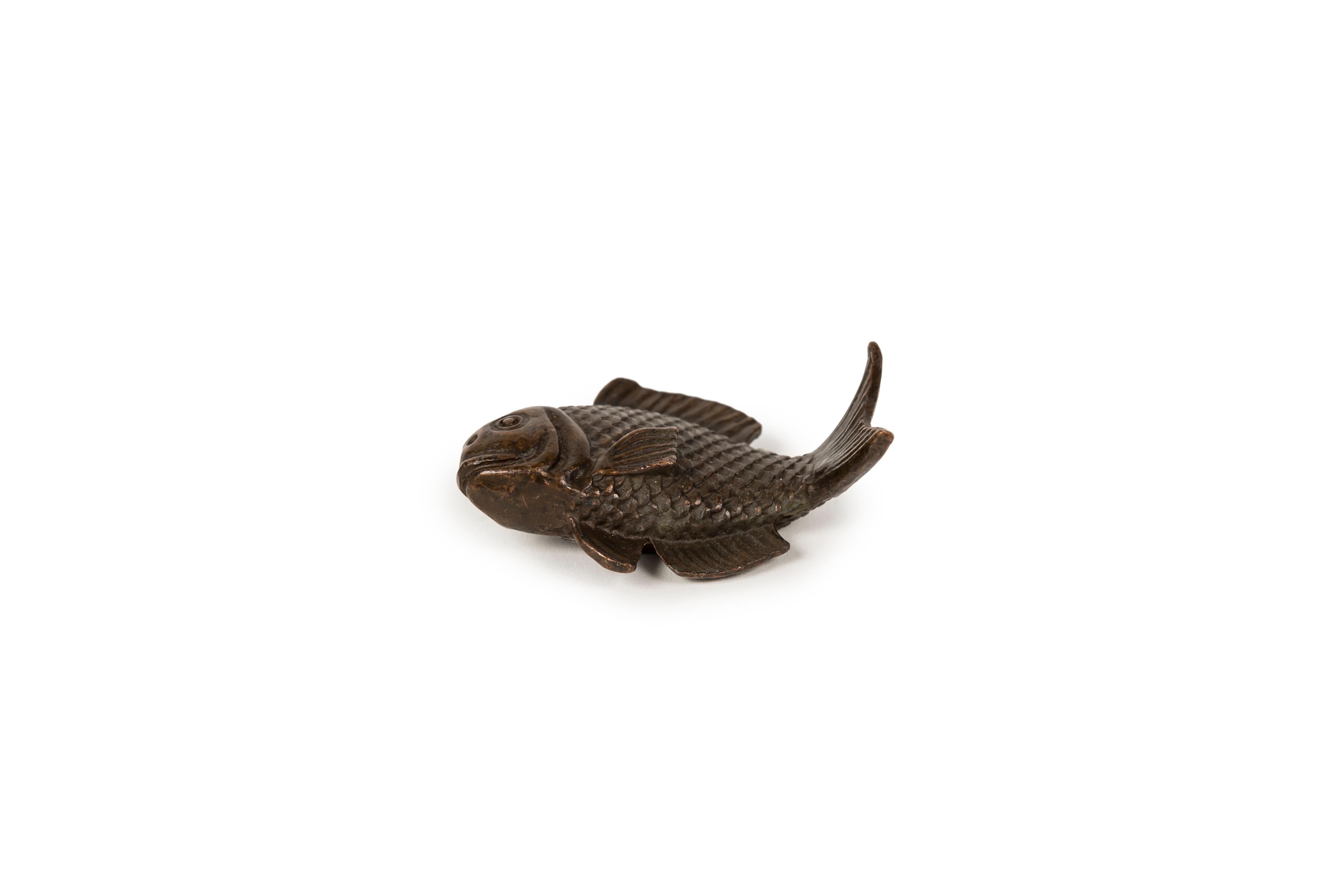 A small but interesting bronze in the form of a fish, with a chocolate-colored patina, probably intended to serve as a calligrapher's weight (bunchin). The treatment of the scales is semi-realistic, reminiscent of classical depictions of fish seen