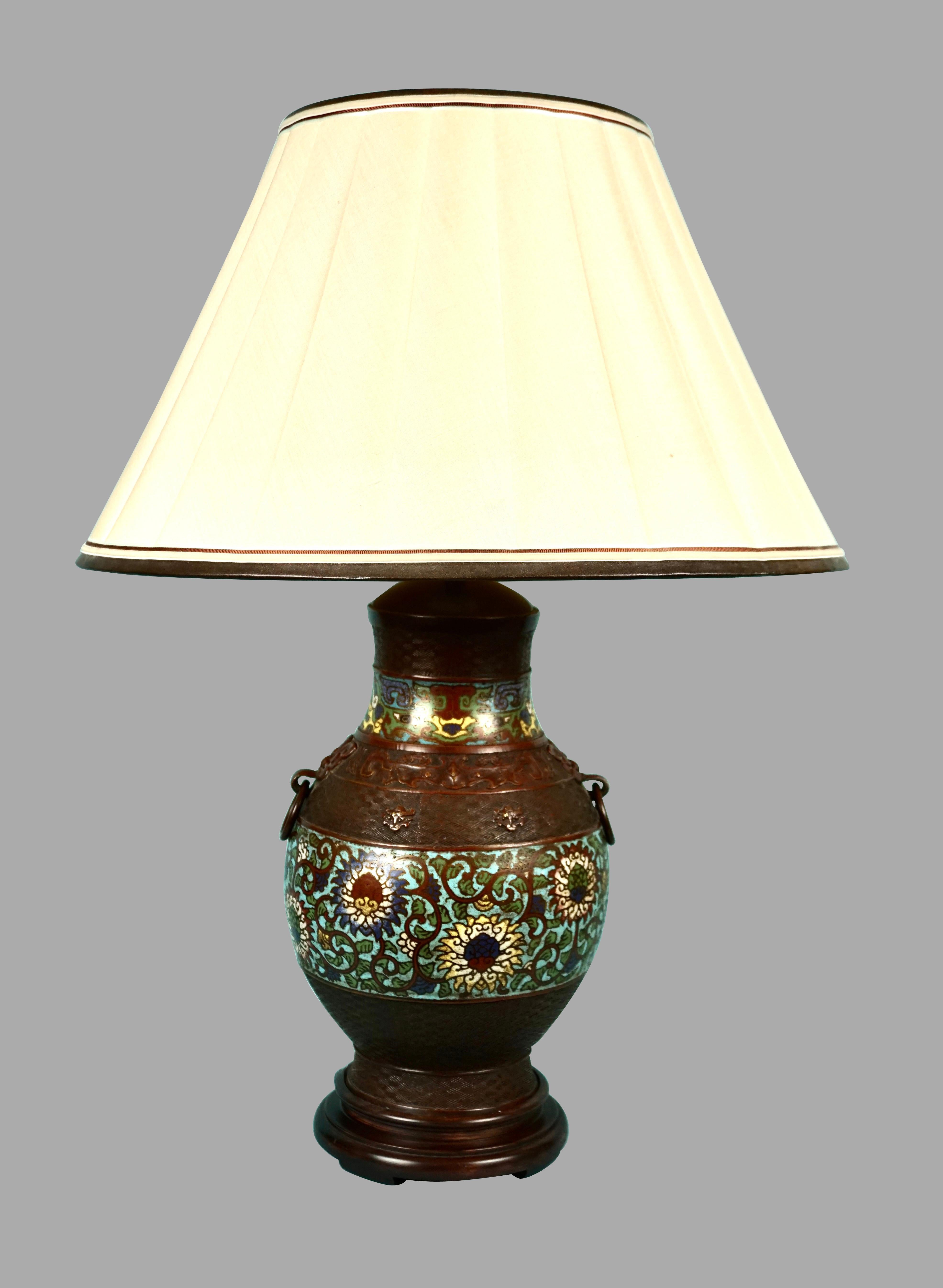 A bronze Japanese champleve vase of baluster form with ring handles and foliate decoration in shades of oxblood, robin's egg blue, ochre, white and forest green.
The vase depicts stylized chrysanthemums, the Japanese national flower symbolizing