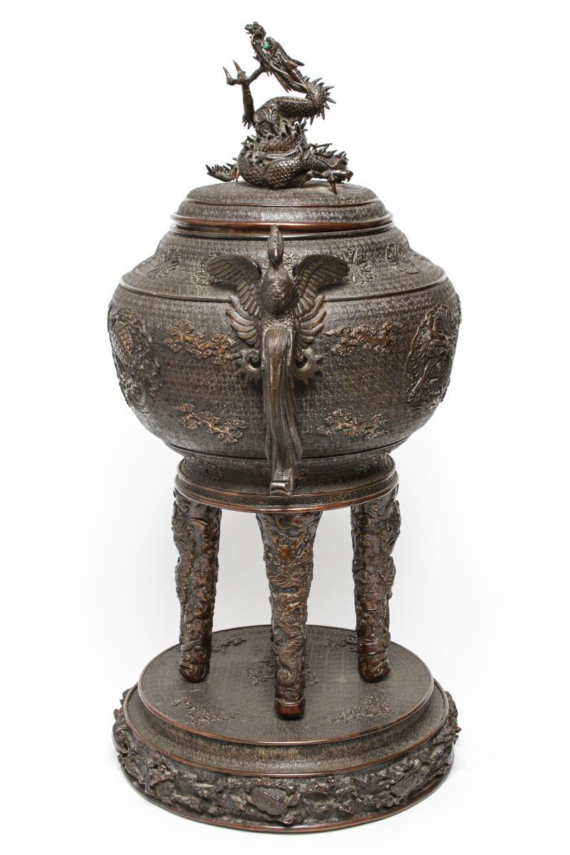 Japanese bronze censor, with phoenix birds on either side of the vessel, with bas reliefs of dragons and phoenixes, supported by four legs atop a circular base with turtles among rock Formations. All creatures have rhinestone eyes.