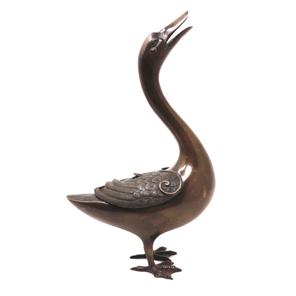 Antique Japanese bronze incense burner in the charming cast form of a goose, standing on both webbed feet, broad body serving as the incense burning receptacle with long outstretched neck and head raised high with beak open in mid-call, the detailed
