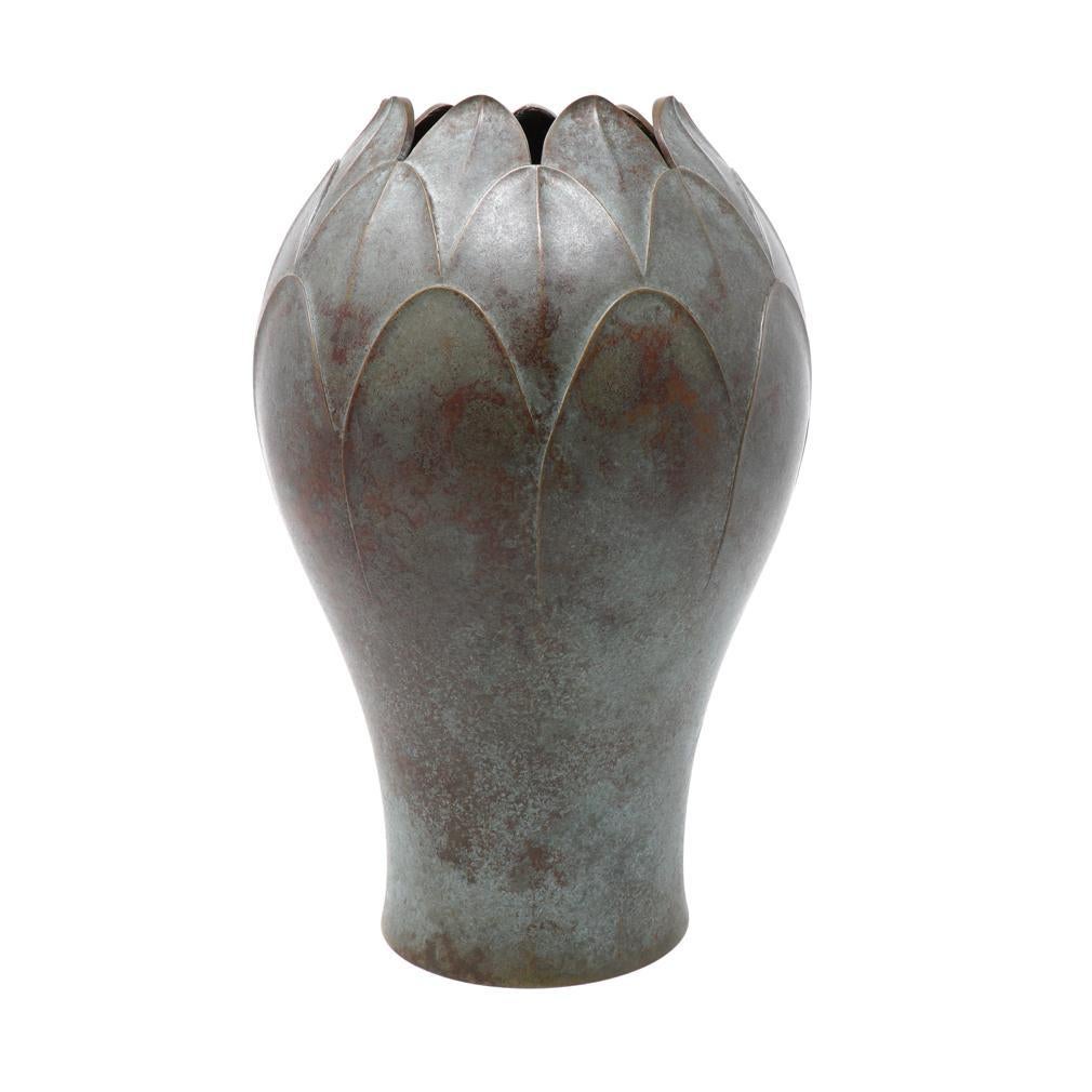 Vaso in bronzo di Hongō Toshihiko con forma di bocciolo di loto, leggermente bulboso con base più stretta. Il disegno in rilievo è costituito da petali di loto sovrapposti e da una finitura verdastra sul corpo in bronzo giallo. Sulla base