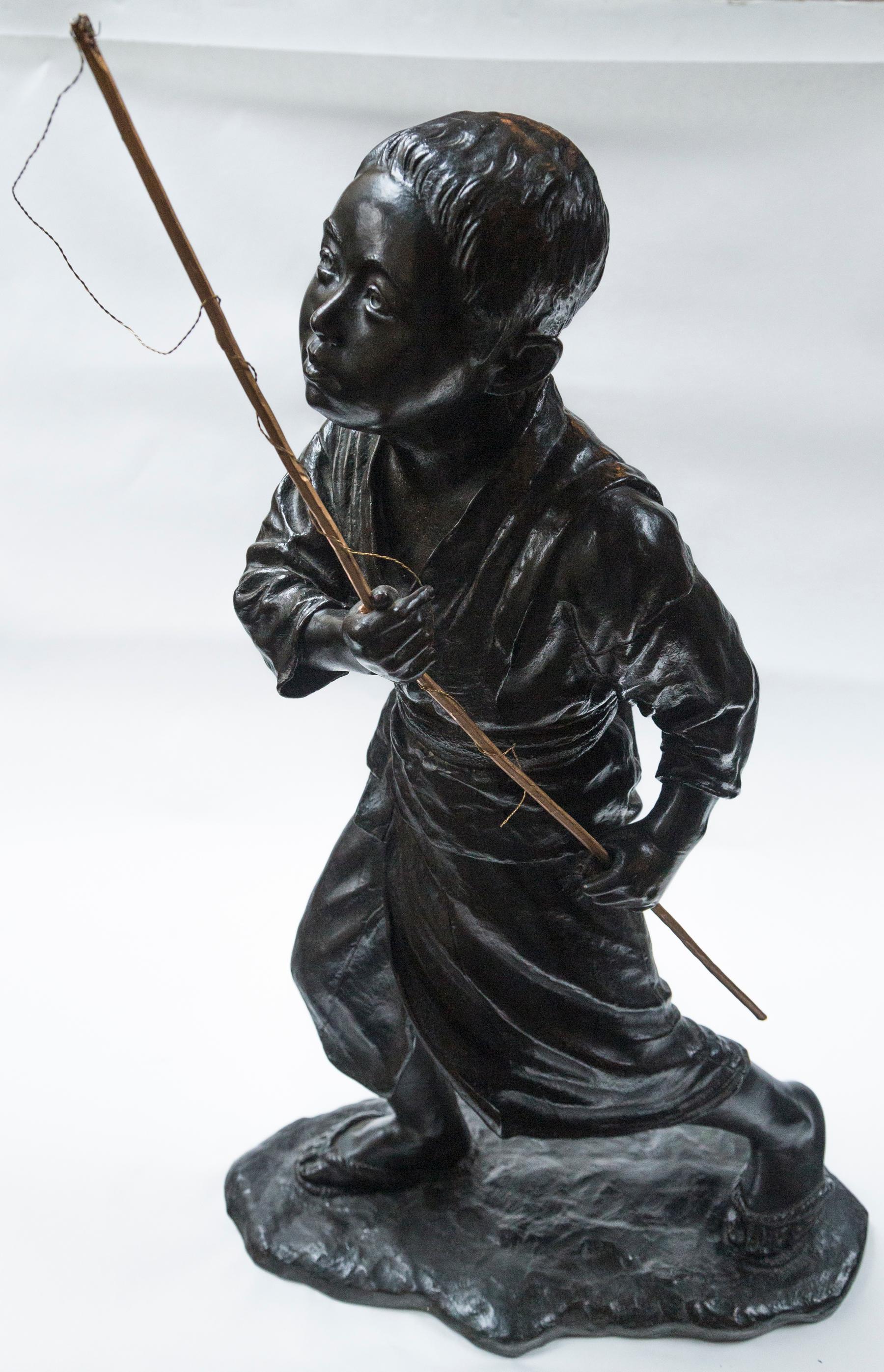 The boy is wearing a robe that is tied at the waist, and rope sandals. He carries a wooden pole with fishing line attached. To the top of the pole from the base is 26 inches. The bronze itself is 25 inches tall. He stands on a natural ground base,