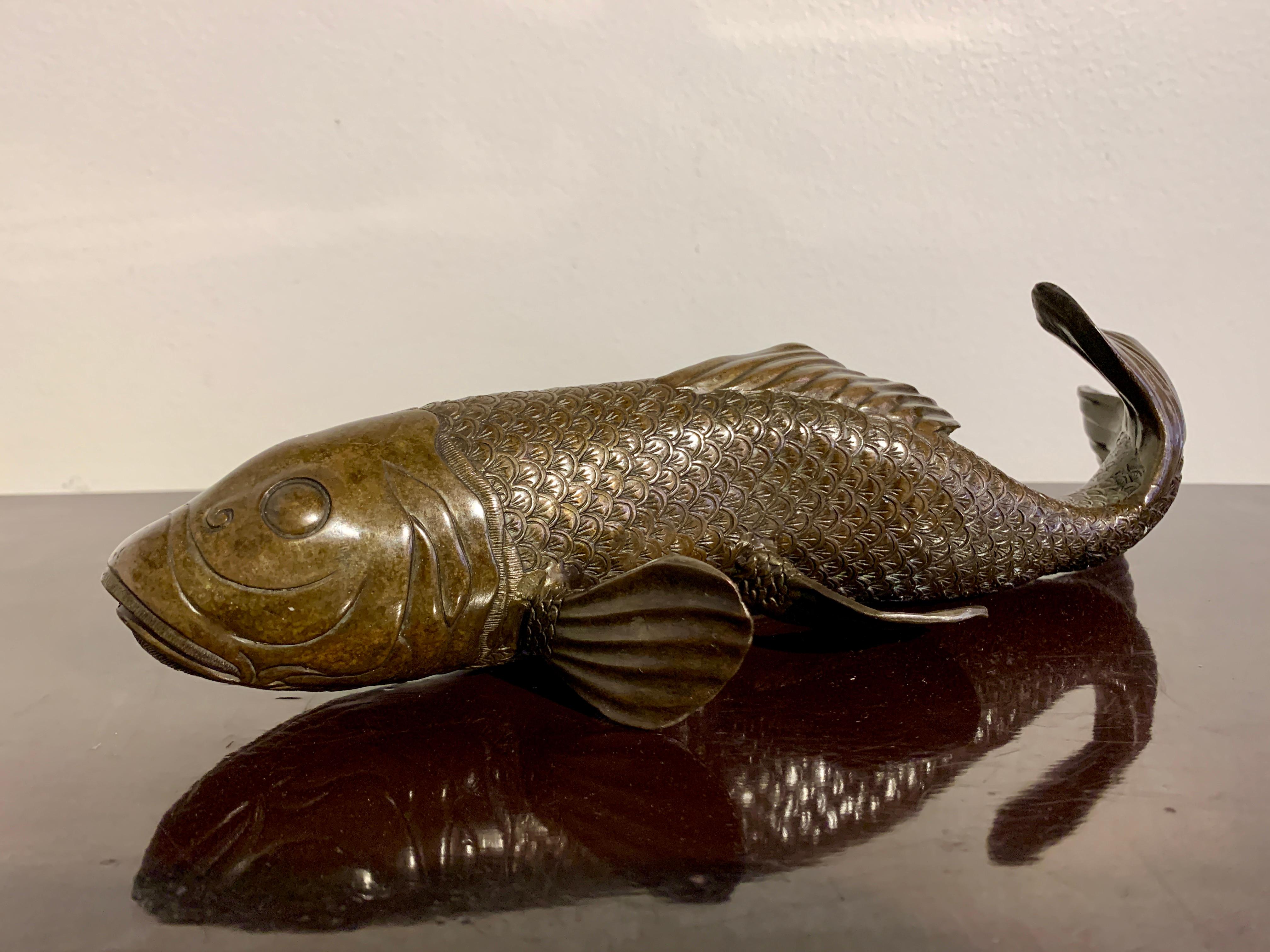 Ein eleganter japanischer Bronzeguss-Okimono eines schwimmenden Karpfens, Taisho-Periode (1912 - 1926), frühes 20. Jahrhundert, Japan.

Die anmutigen Fische sind realistisch in Bewegung dargestellt, als würden sie gegen eine Strömung schwimmen. Die