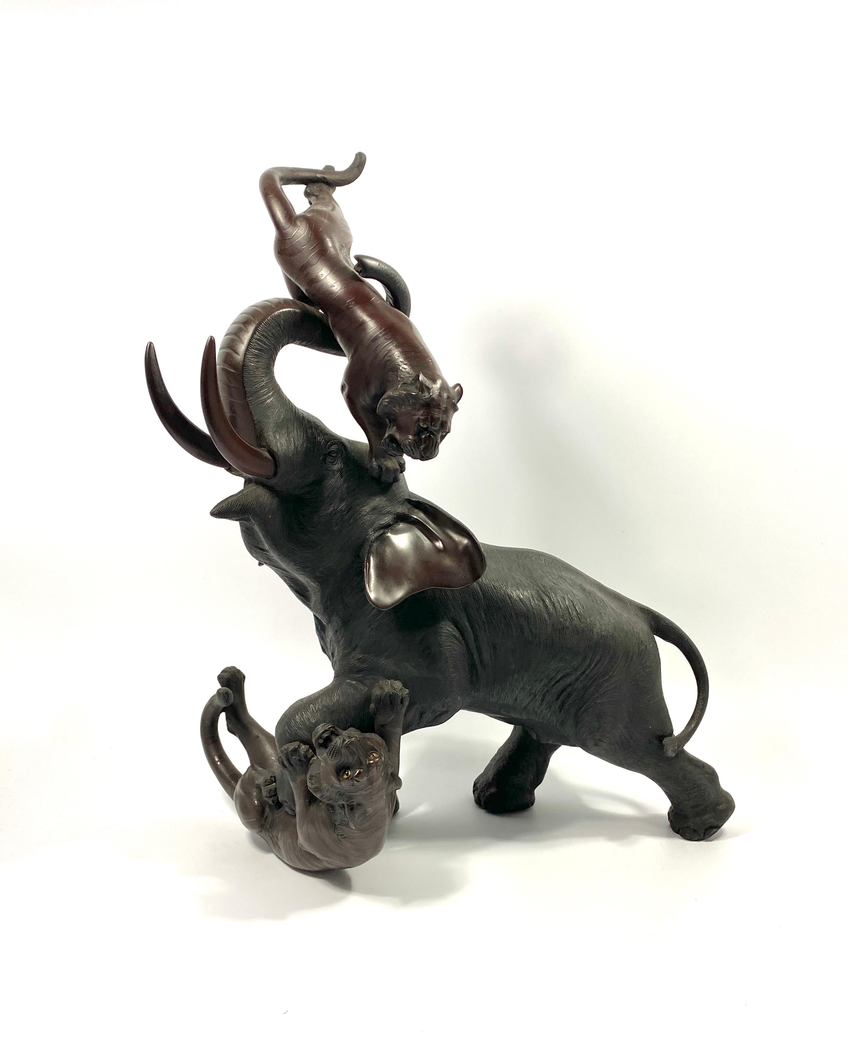 Un okimono giapponese in bronzo di grandi dimensioni, Omori Mitsumoto (Kogetsu) Saku, periodo Meiji. Un elefante che lancia una tigre con la proboscide, mentre un'altra tigre è intrappolata sotto di lui. I dettagli della pelle degli elefanti e delle