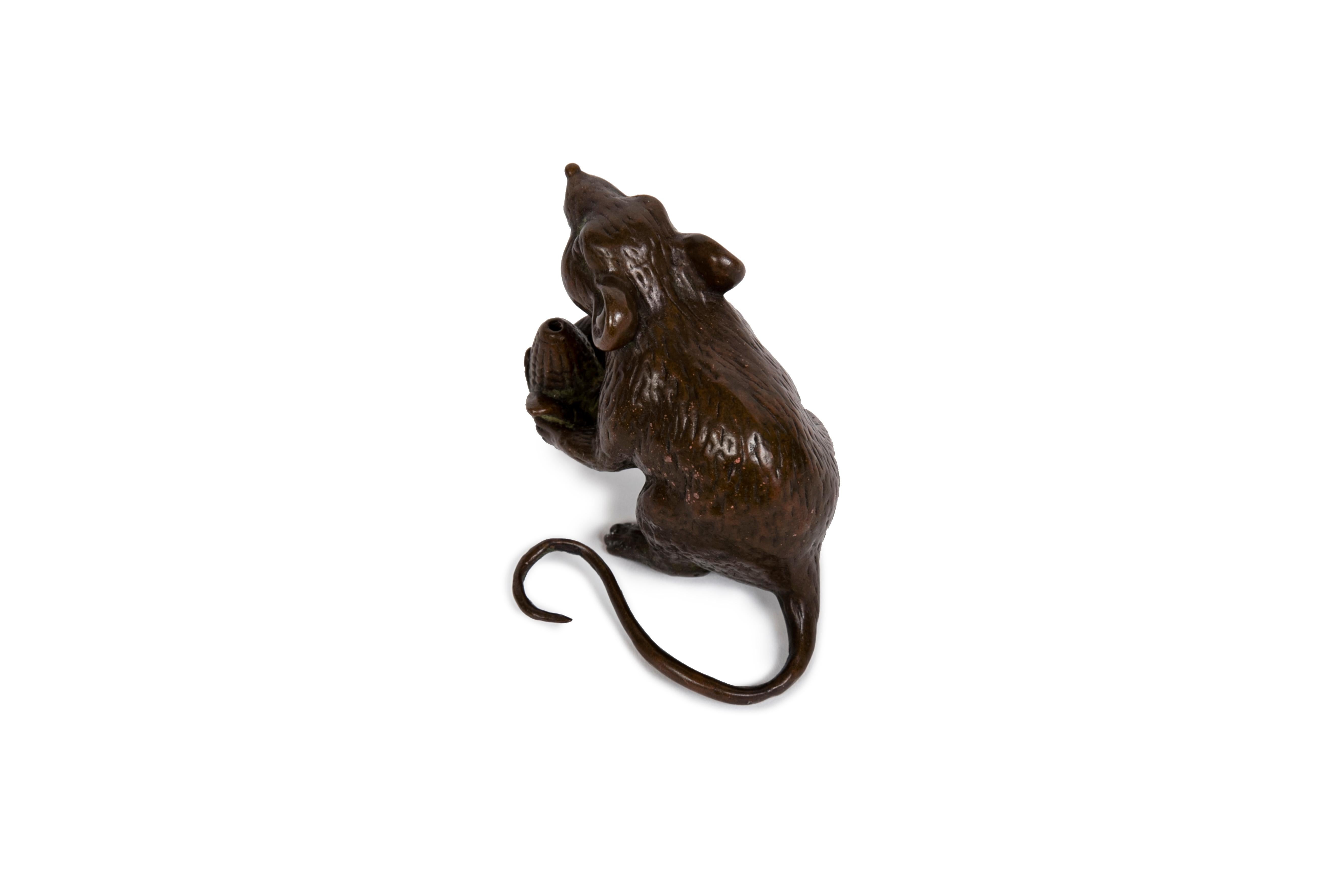 Un'interessante scultura in bronzo raffigurante un topo seduto che tiene in mano una piccola manopola di mais. Trattamento realistico della pelliccia, degli occhi, del naso e della bocca, la coda si incurva sul lato sinistro del soggetto. Sebbene
