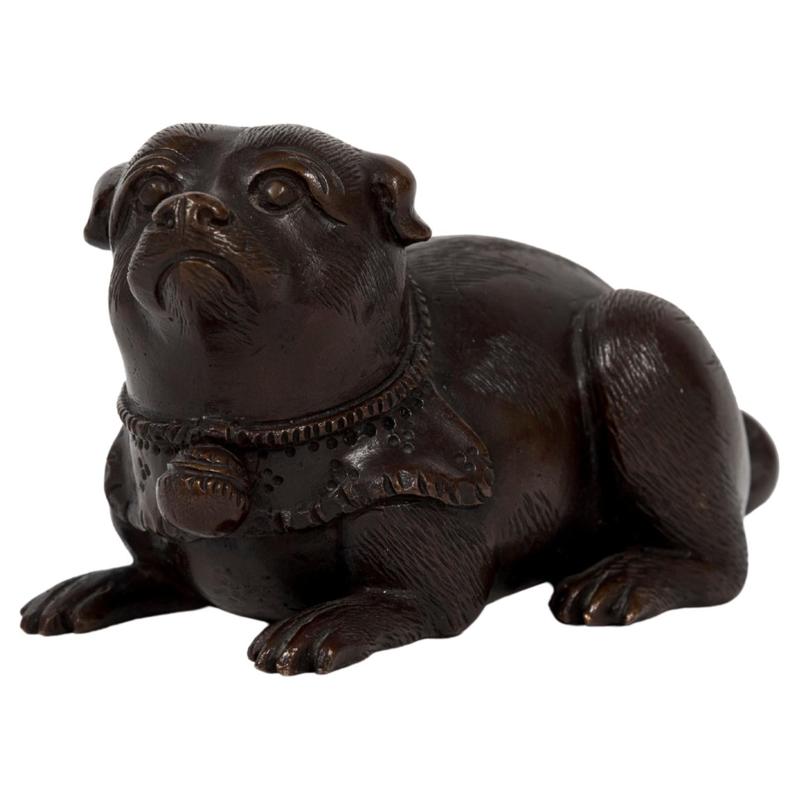 Escultura japonesa de bronce que representa a un cachorro tumbado
