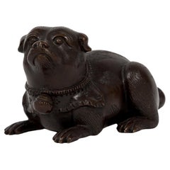 Escultura japonesa de bronce que representa a un cachorro tumbado