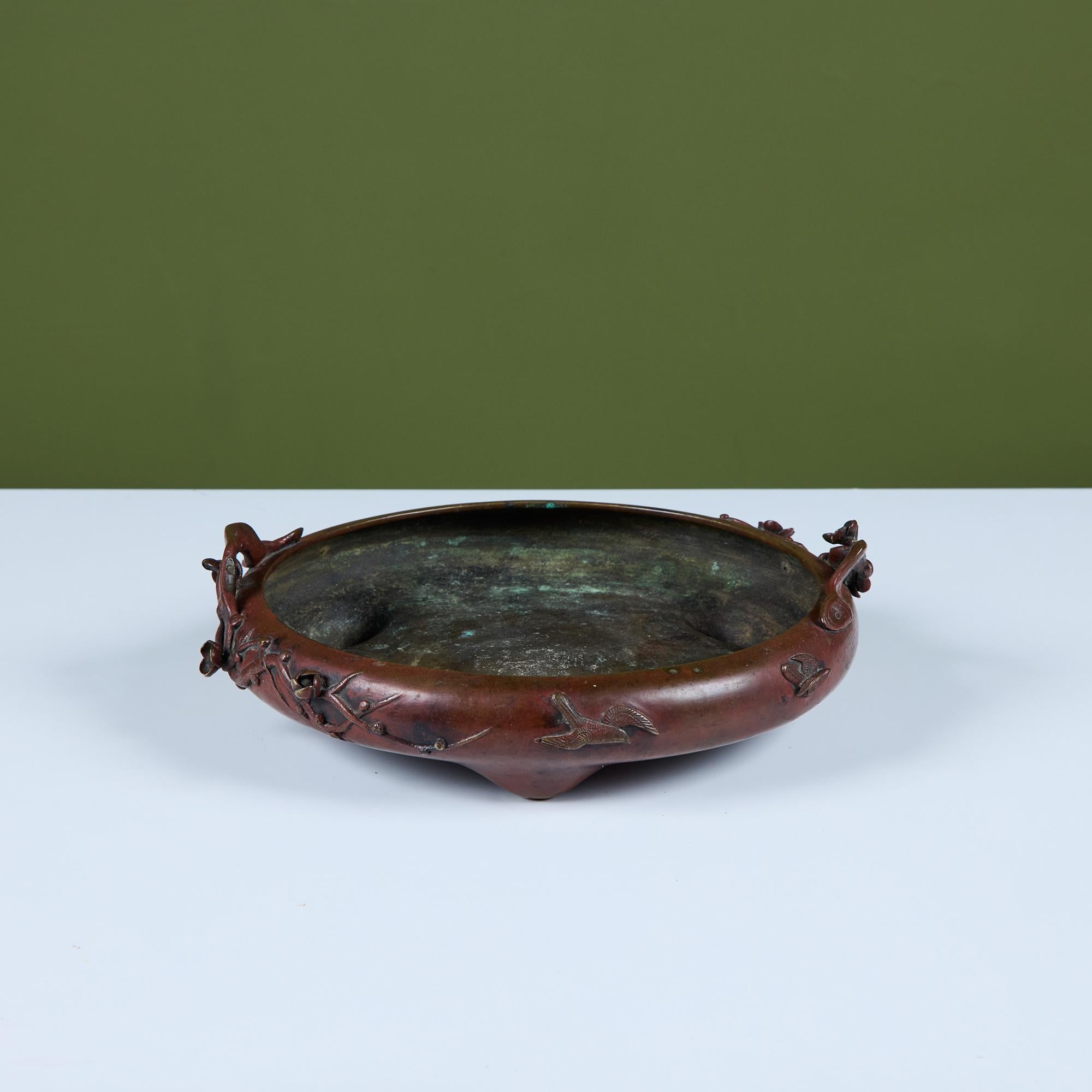 Round Suiban Ikebana bowl vase with hints of verdigris. The bronze piece showcases a floral motif around the exterior of the bowl and sits atop three pointed feet.

Dimensions
12” diameter x 3.5” height.

Condition
Good vintage condition;