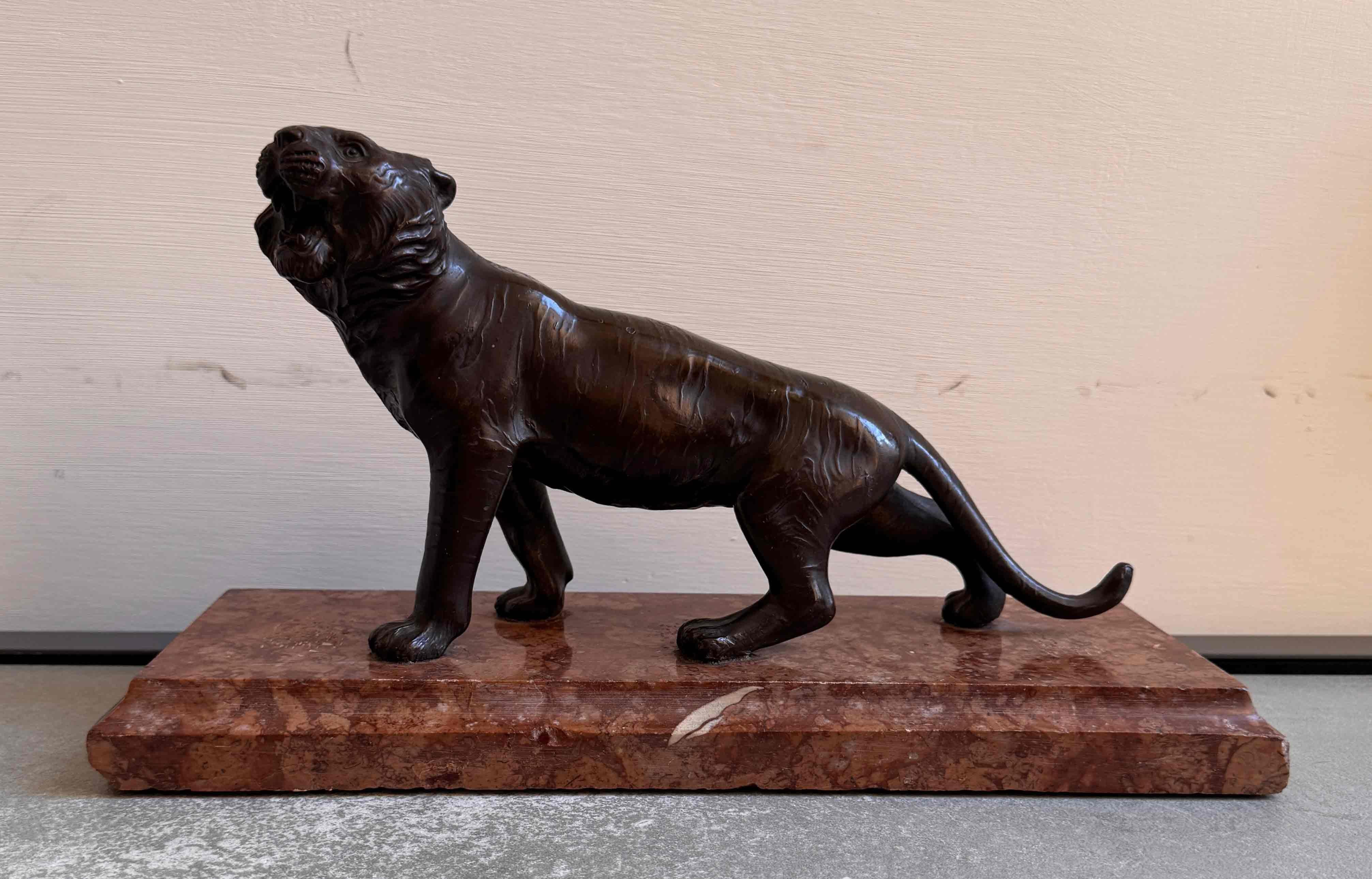 Elegante scultura in bronzo raffigurante una tigre ruggente, finemente fusa con una muscolatura dettagliata, una testa espressiva e una pelliccia dalla consistenza naturalistica.
L'animale si trova in una posa dinamica su una base rettangolare in
