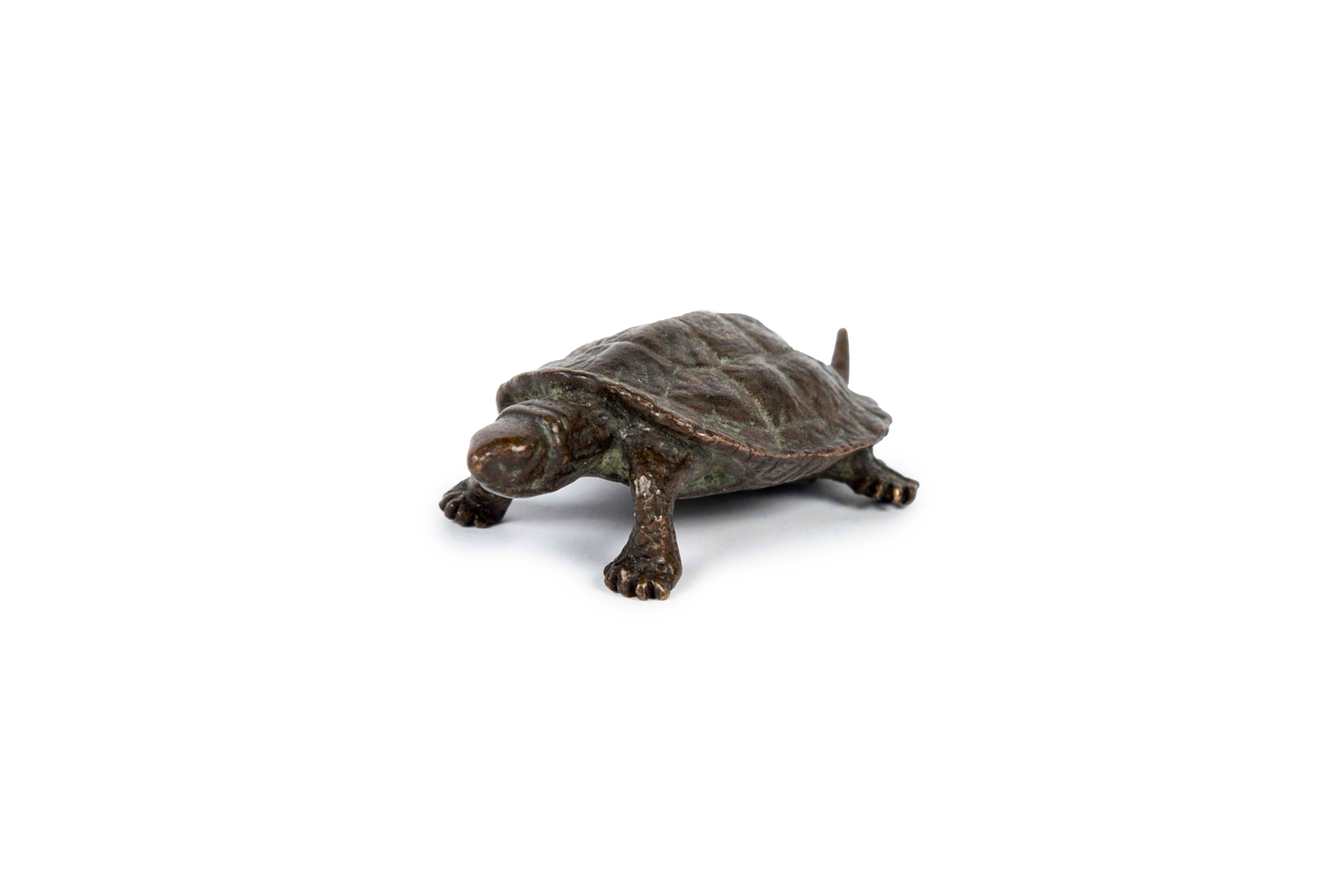 Okimono-Skulptur einer Schildkröte aus Bronze, mit einziehbarem Schwanz.
In Japan ist die Schildkröte (kame) ein Symbol für Langlebigkeit und ein glücksbringendes Tier.
Sie soll zehntausend Jahre Glück bringen.
Signiert Hata (はた) auf der Unterseite