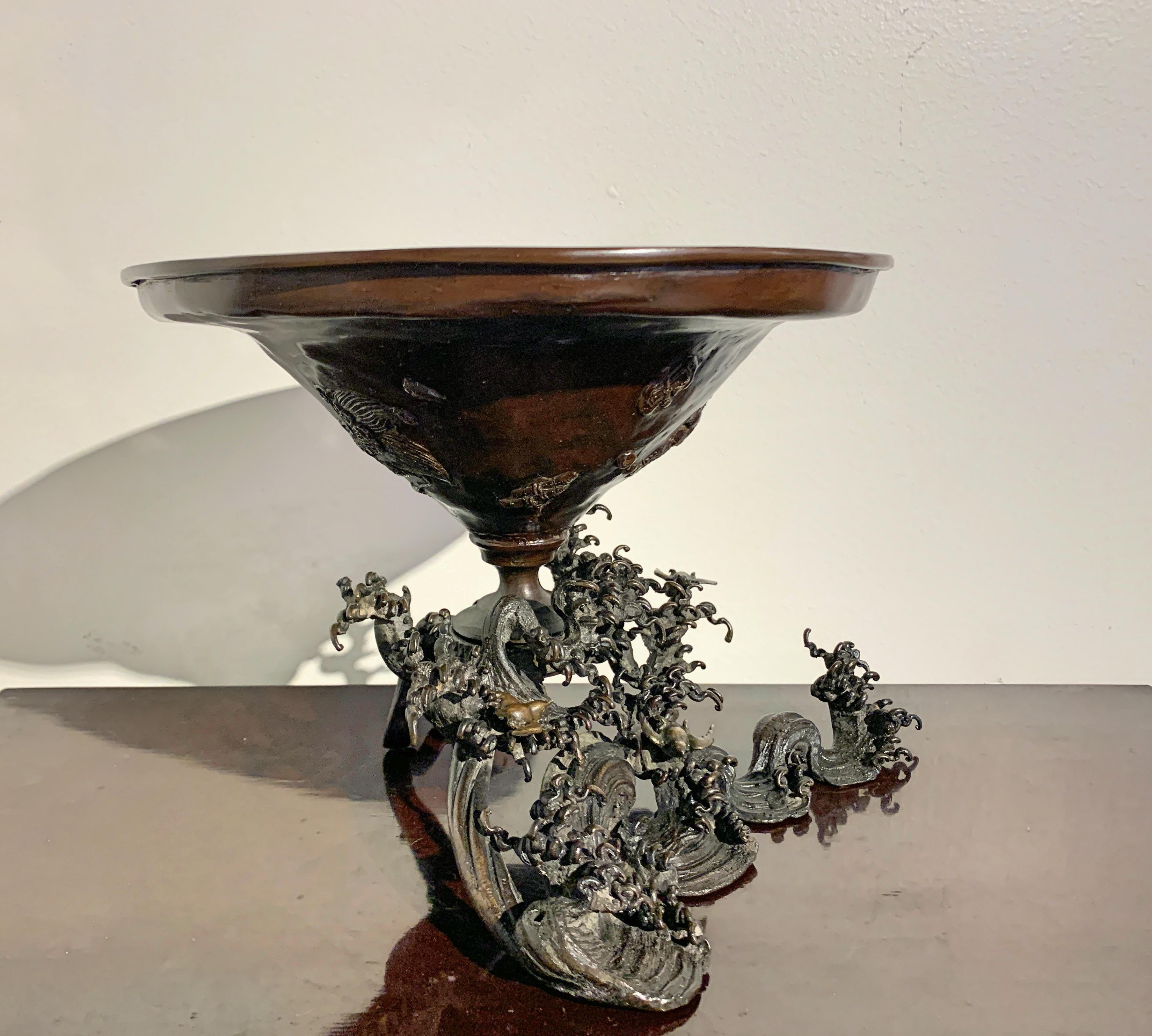 An impressive Japanese cast bronze usubata, vessel for ikebana, in the form of a large conical vessel being supported by crashing waves and flying chidori. Edo Period, mid-19th century or earlier, Japan.

An usubata is an essential vessel for some