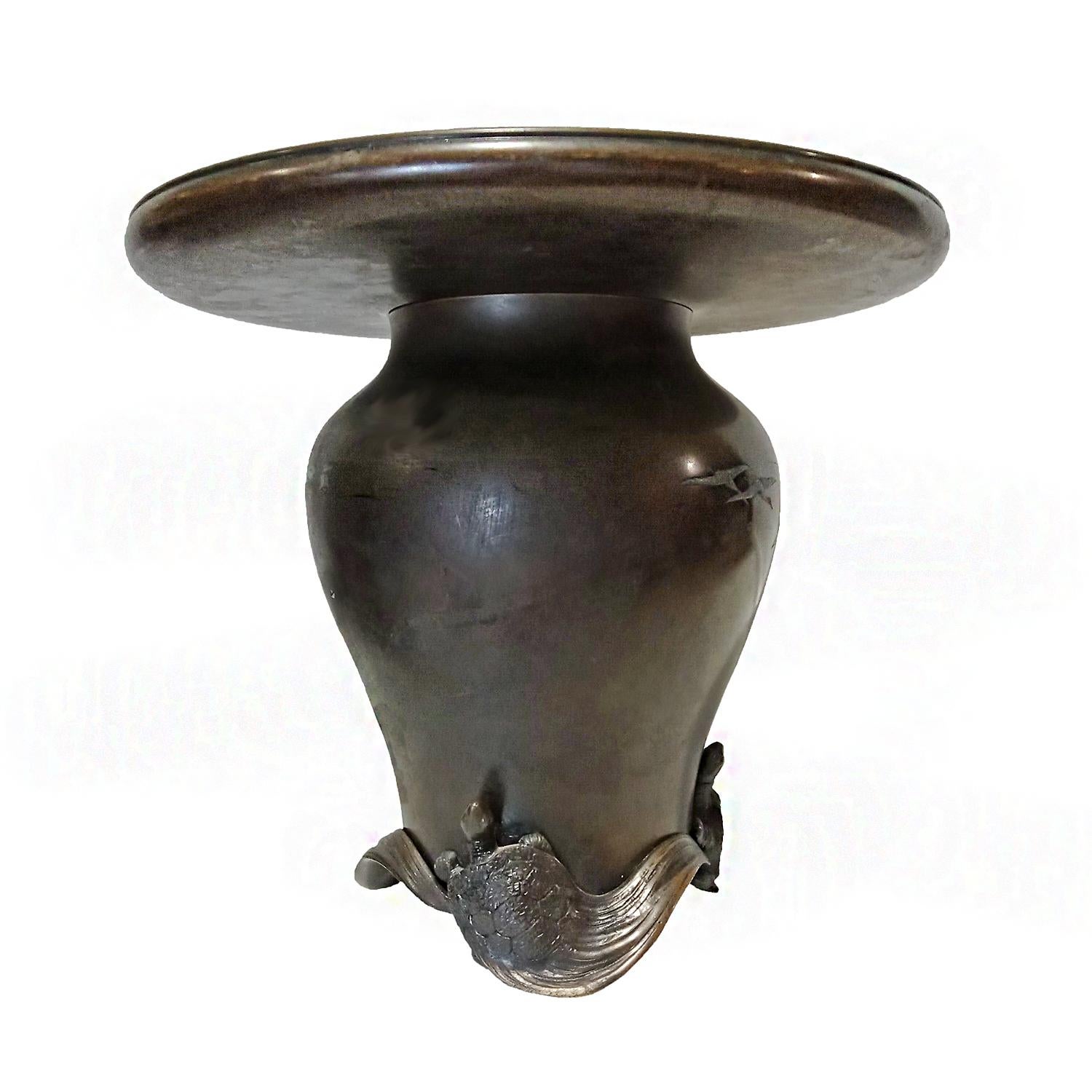 A unique Japanese vase, hand-crafted in bronze. Meiji Period, circa 1890. Decorated with embossed cranes and a gilt sun symbol. At the bottom, the vase is nested in an exquisitely carved base with three turtles, which according to traditional