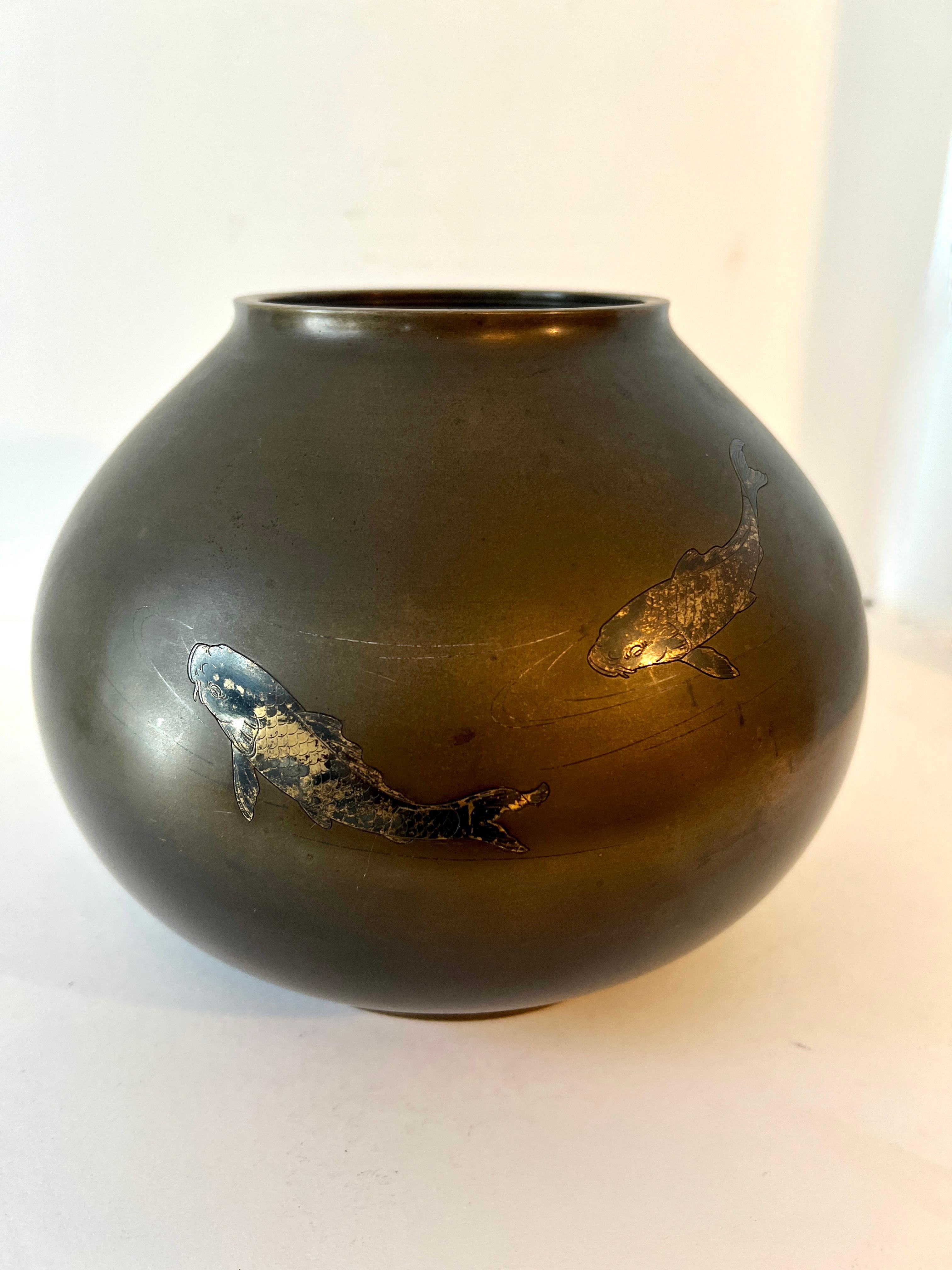 Eine außergewöhnliche kugelförmige asiatische Vase mit geätzten Koi-Fischen mit Silbereinlage, umgeben von anmutigen und minimalistischen Wasserfetzen.

Das Stück ist eine perfekt patinierte Vase aus schwerer Bronze mit Linienätzungen und einem Paar
