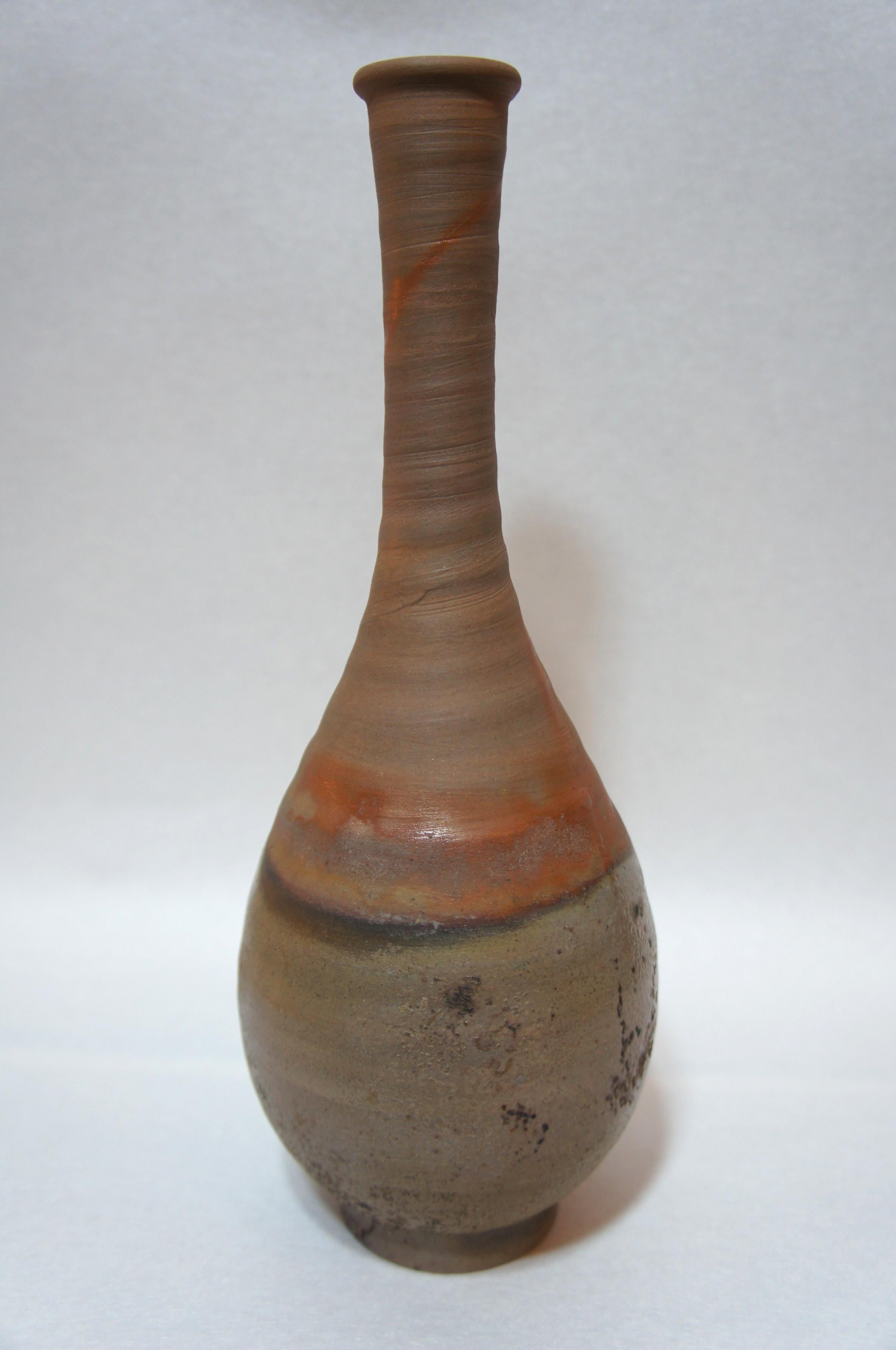 Beautiful brown and orange unglazed Bizen ware vase.
On the bottom side, there is a sign of a Japanese artisan.

Bizen Ware is pottery and tunnel kiln made in Bizen province, presently part of Okayama prefecture in Japan. The kiln is one of the
