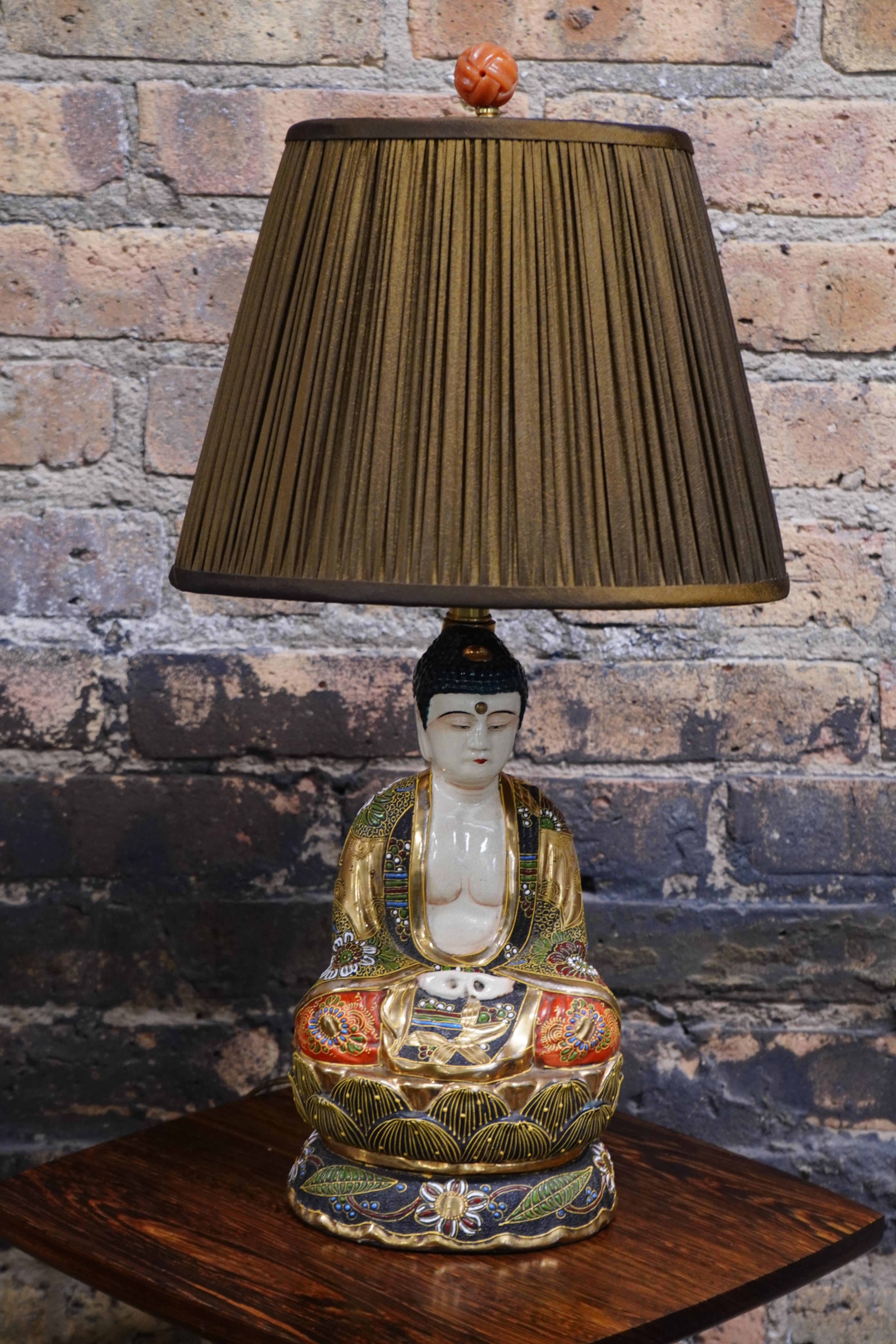 A lovely Japenese Satuma pottery Buddha lamp. Ornately decorated with an opening at the back for the lamp's cord. 

It has a varied color palette; cream, black, red, green and accentuated with gilding.  