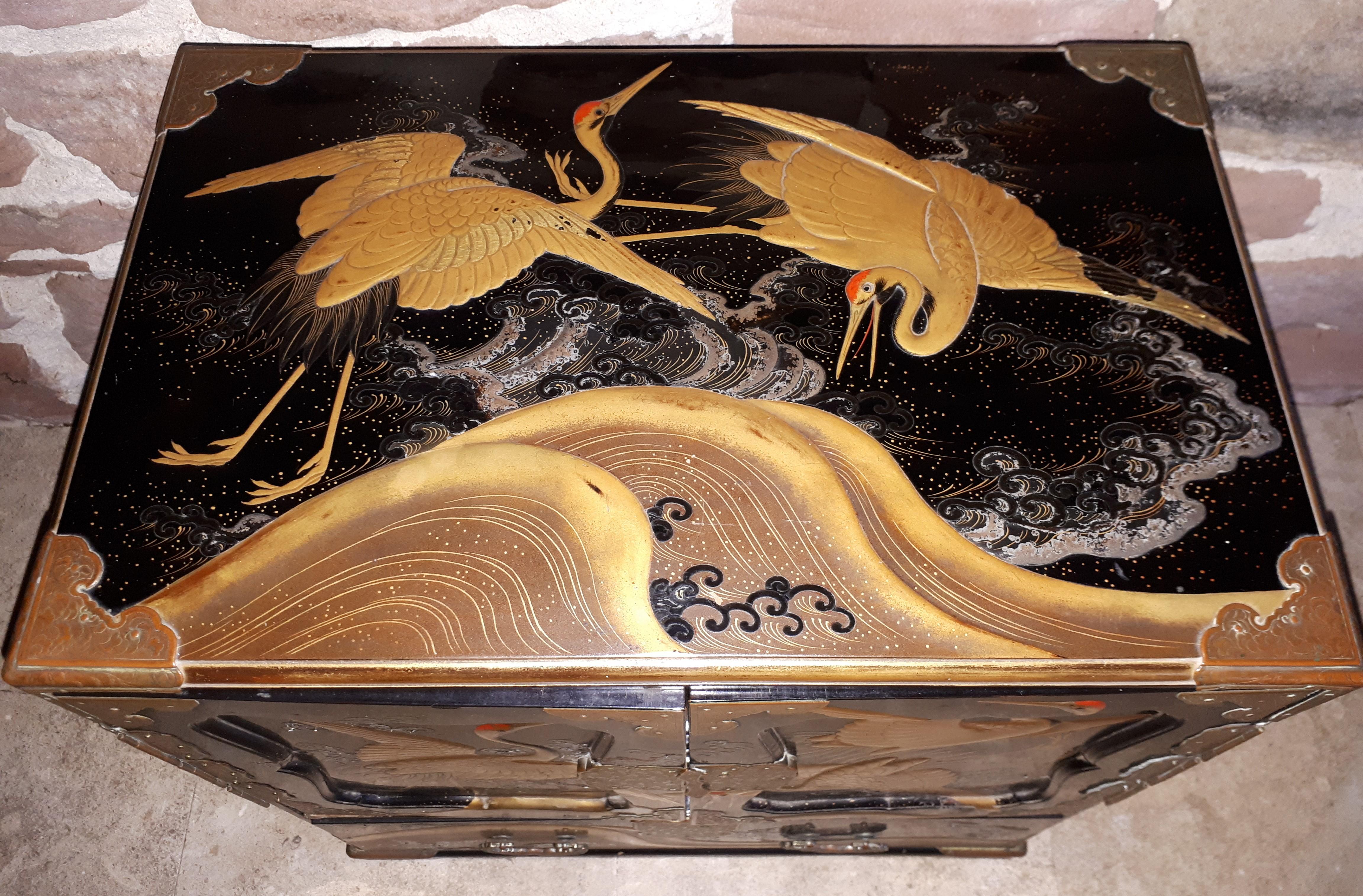 Precious lacquer cabinet with two leaves and a drawer decorated with cranes flying over the waves, revealing six small drawers decorated with seafood. It surprises by the variety of techniques used: e nashiji for seafood, heidatsu or hyômon (cut