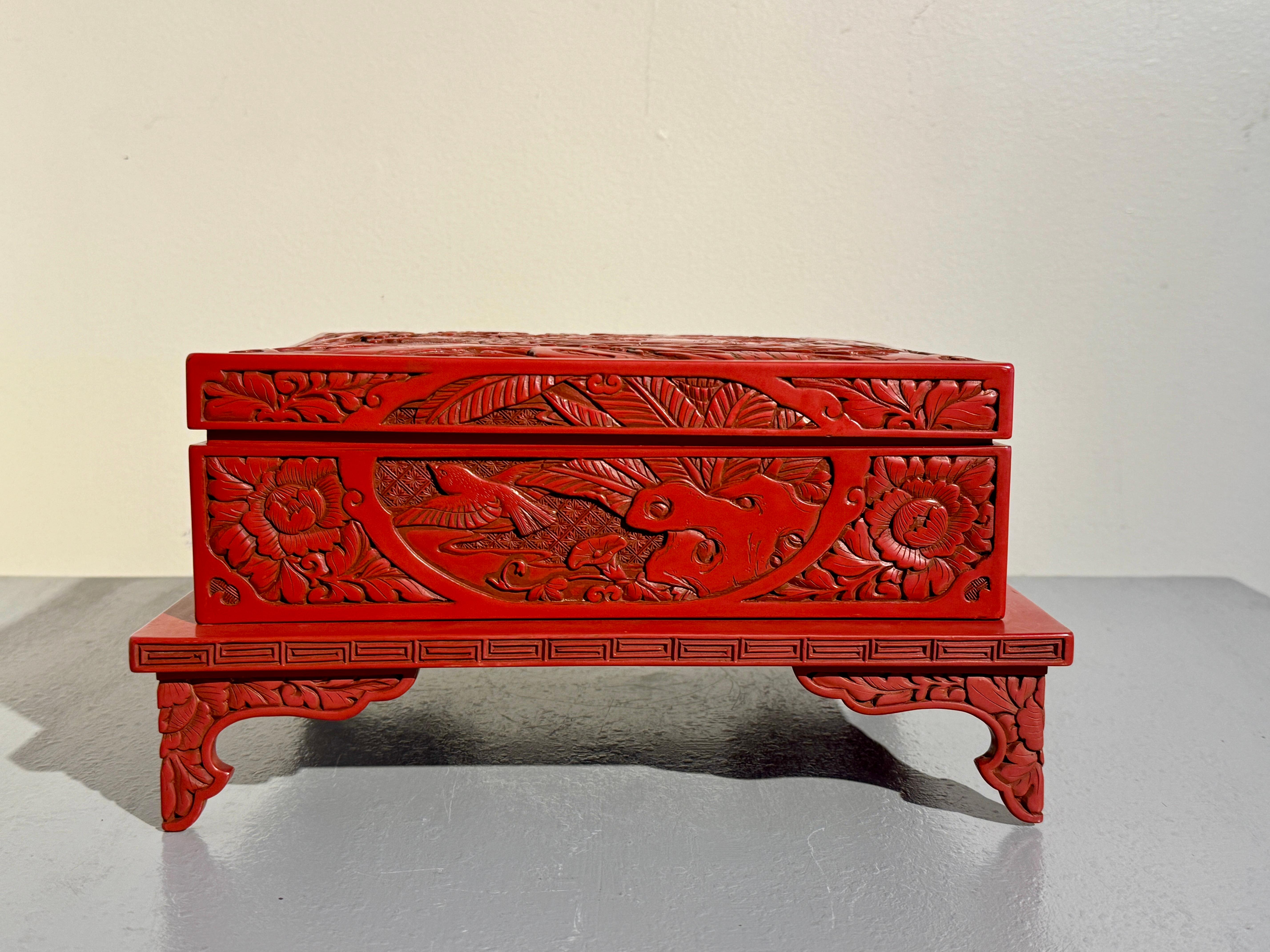 A nice and highly decorative Japanese carved red lacquer covered box on stand, Showa Era, circa 1930's, Japan.

The rectangular box is heavily carved all around and covered in a vibrant and attractive red lacquer. The lid features a scene of two
