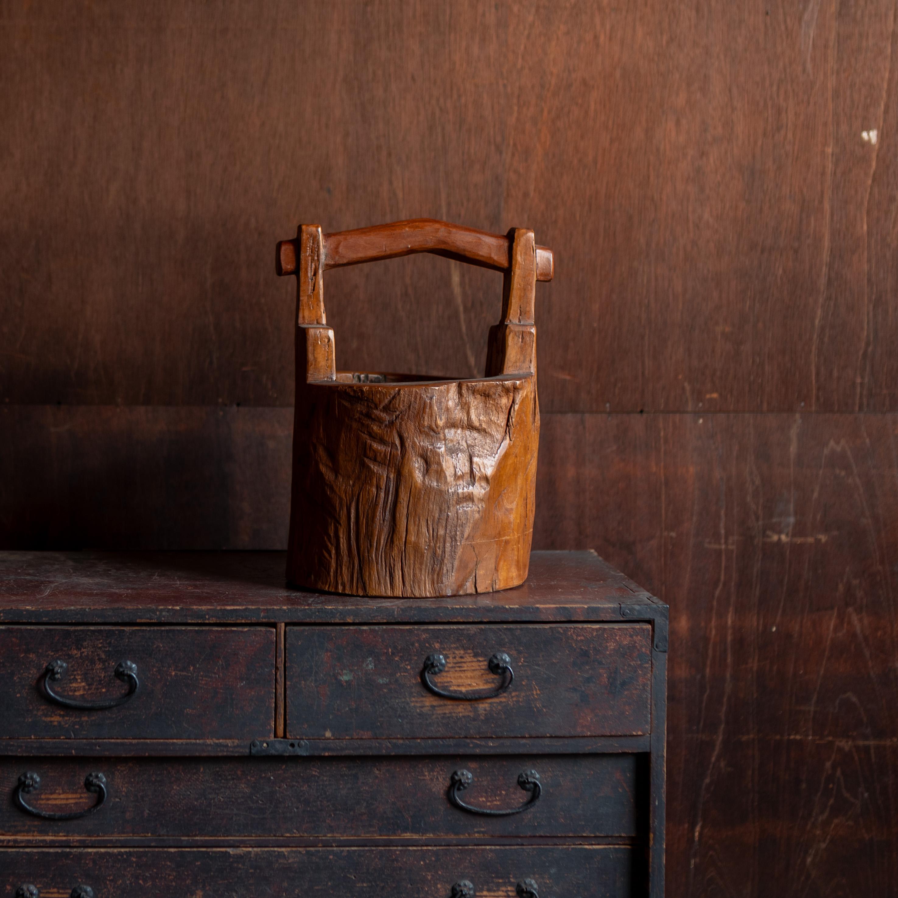 Recipiente floral japonés de madera finamente tallada con forma de cubo tradicional (oke). Asociada en su día con la estética de la cultura del té y la exhibición de flores estacionales, esta pieza encarna los principios del wabi-sabi a través de su