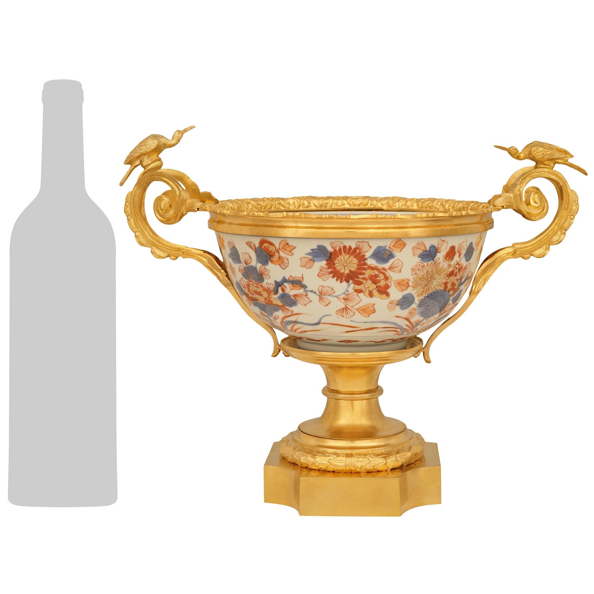 An elegant Japanese 19th century Imari Porcelain and French 19th century Louis XVI st. Ormolu mounted centerpiece. The charming centerpiece is raised by a square Ormolu base with concave corners. Above the base is a richly chased berried laurel band