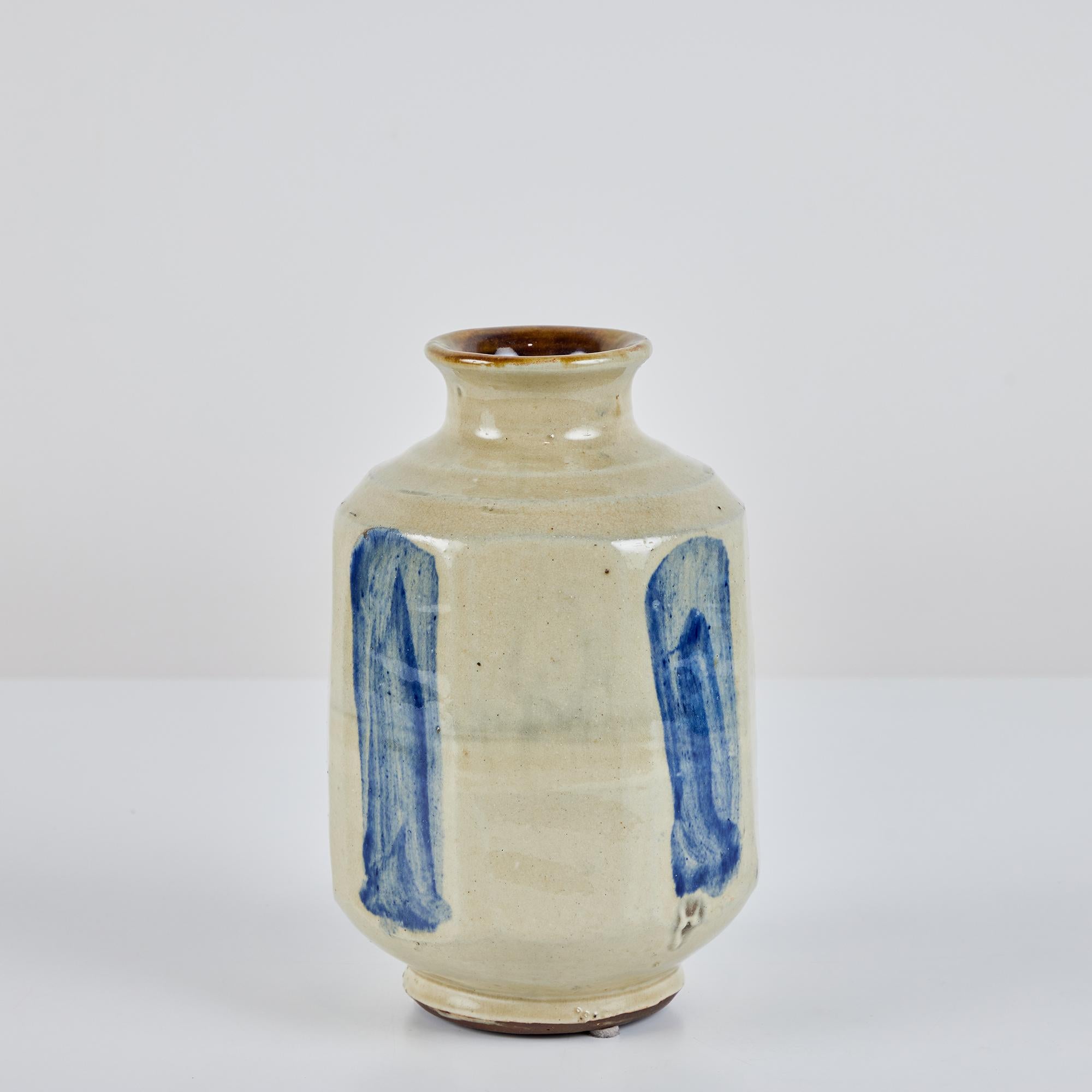 Eine längliche, achteckige Vase aus Studio-Keramik mit ausgestelltem Rand. Dieses Gefäß weist eine ganzflächige beige Glasur mit vier blauen Buschstrichen auf.
Auf der Unterseite signiert.

Abmessungen
5,5
