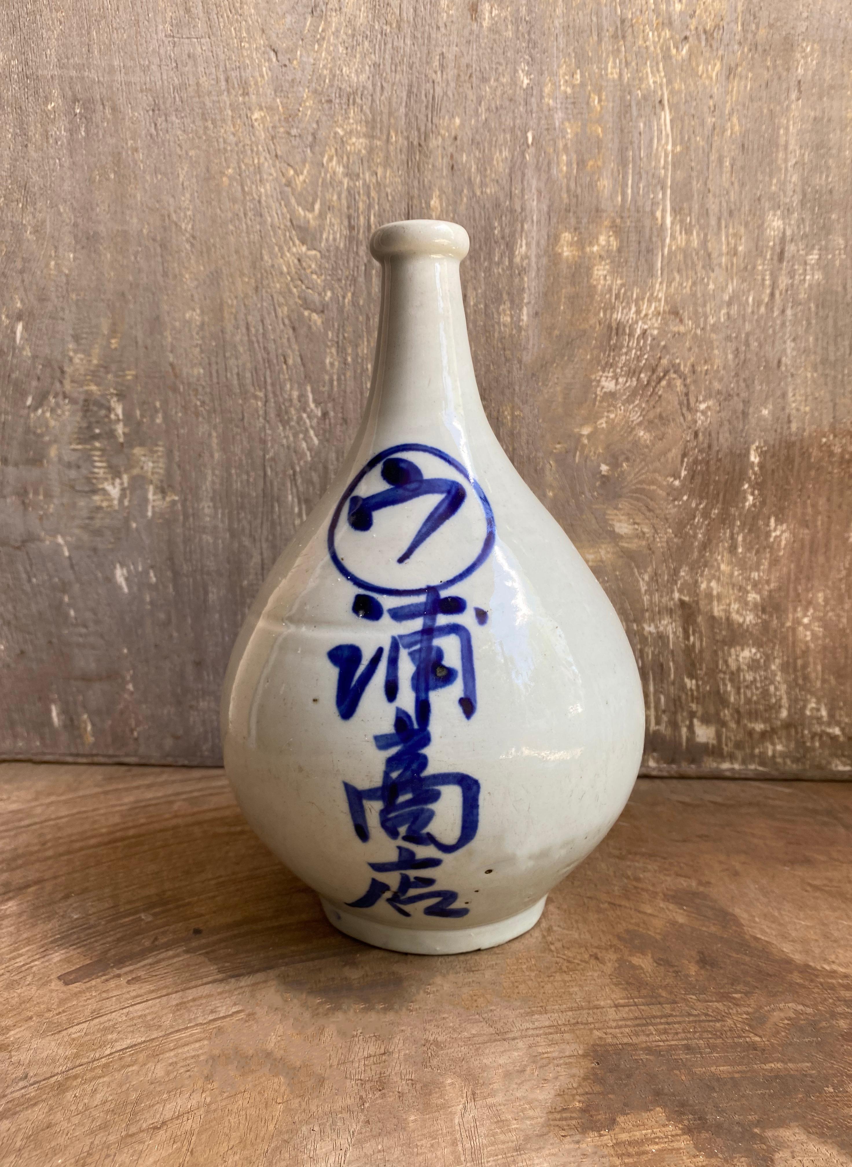 A Japanese ceramic Sake Jar from the early 20th century. The jar features glazed ceramic and hand-painted characters. 

Dimensions: Height 27cm x diameter 17cm.

 