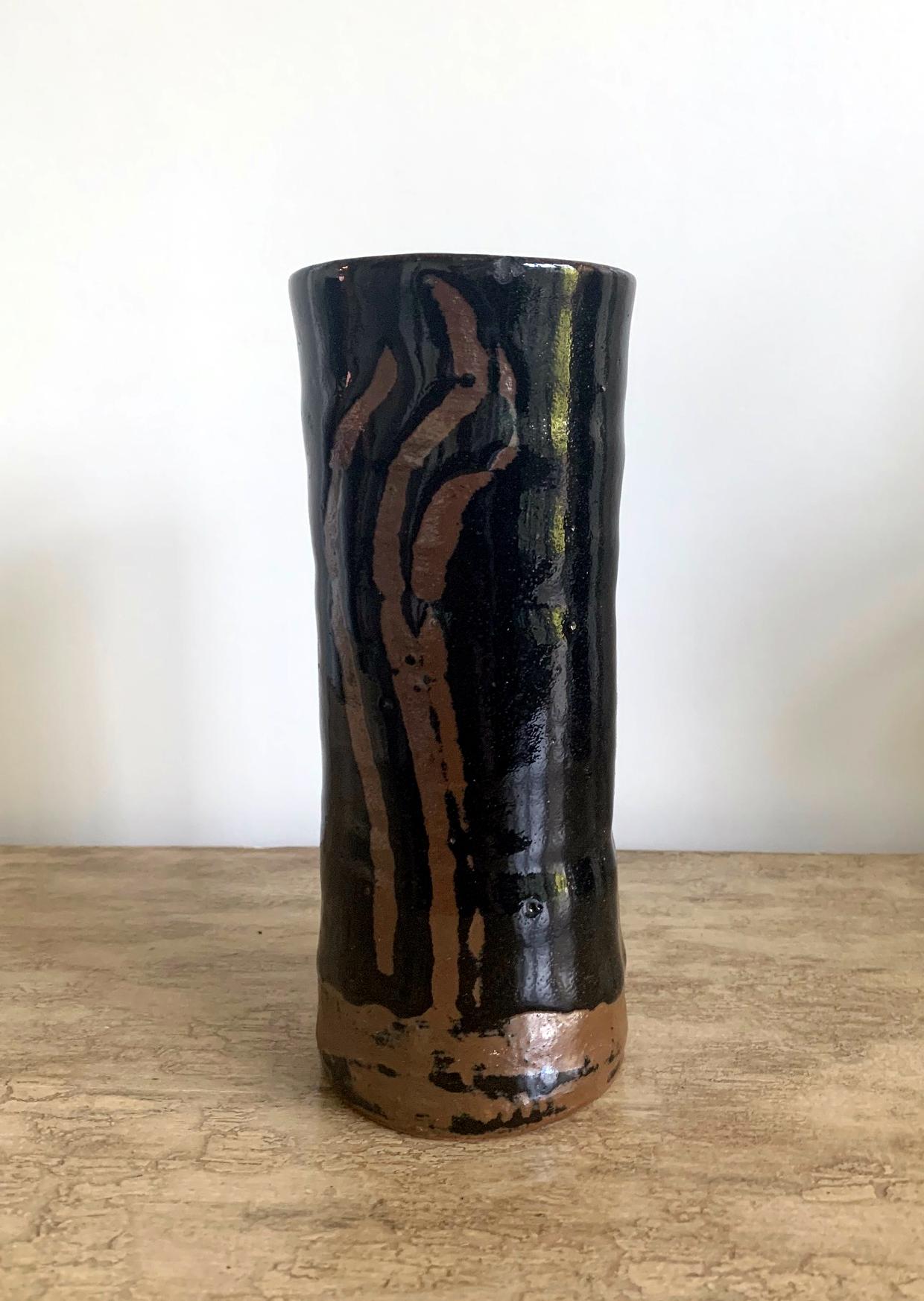 A heavily potted stoneware vase in cylindrical form, decorated with abstract strokes in iron rust glaze (known as Persimmon Glaze in Japanese) on a black glazed background. The pattern suggests autumn grasses, and it was applied with free hands. The