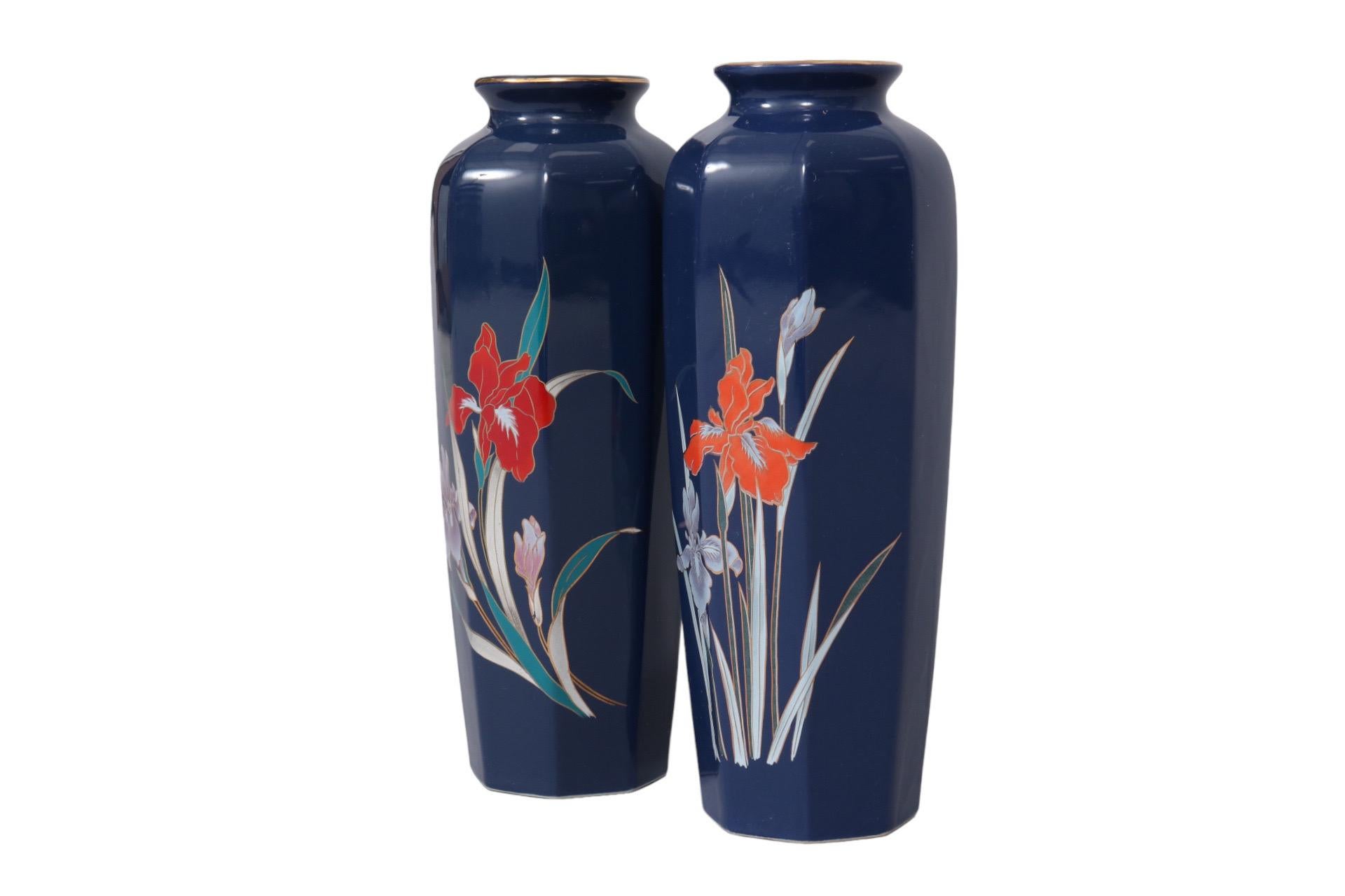 A near pair of Japanese fine China vases in navy blue. Octagonal bodies are hand painted in front with gilt lined bold red and lilac tiger lilies. A shallow neck is lined with gold. Marked ‘fine China Japan’ underneath. Dimensions per vase.