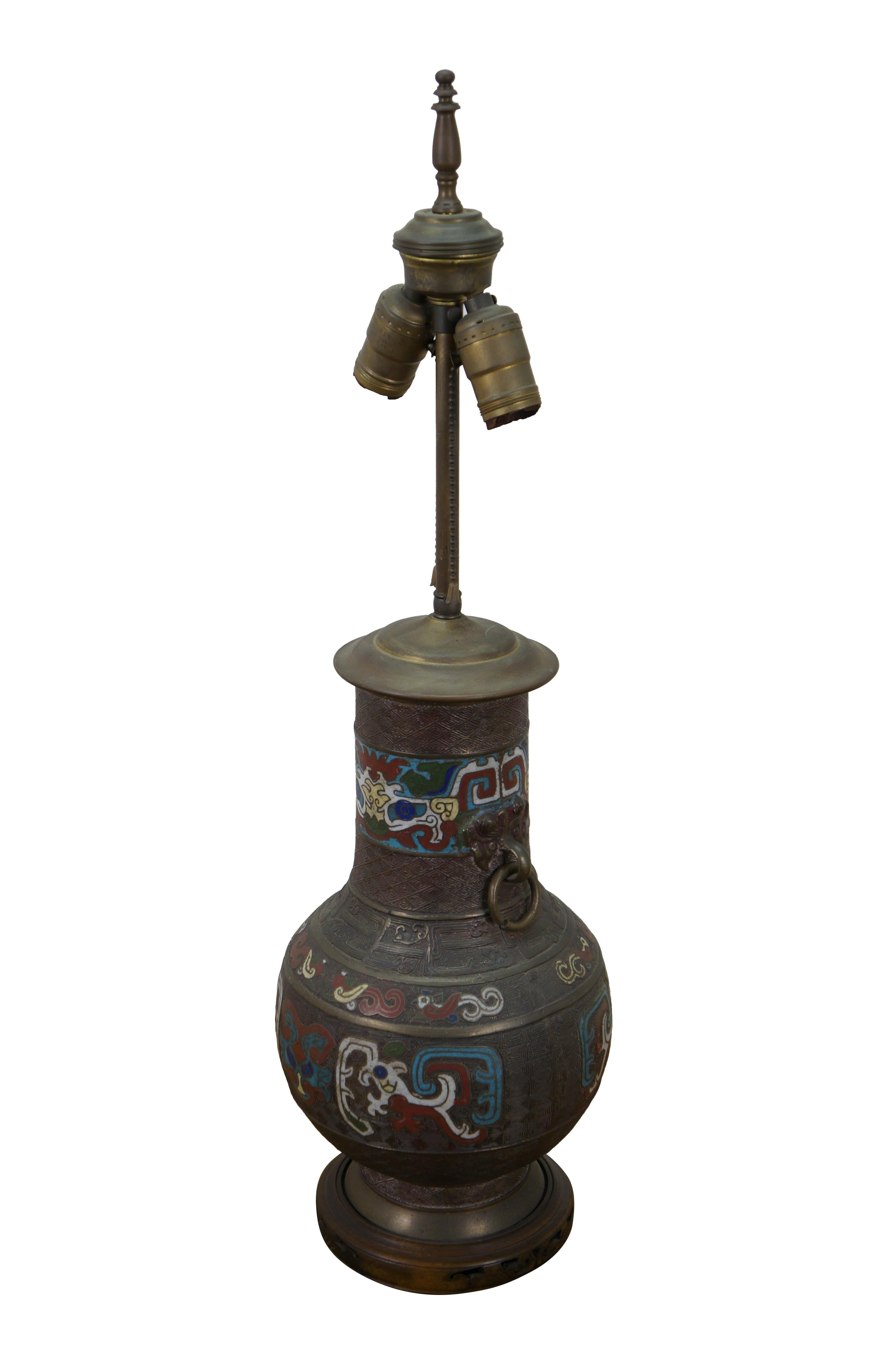 Japanese enameled bronze mantel vase / urn, fitted with a two light pull chain.  It features an urn with rings on either side, decorated with animal motifs in multicolored enamel. Carved wood base. Includes brass finial.

Dimensions:
8