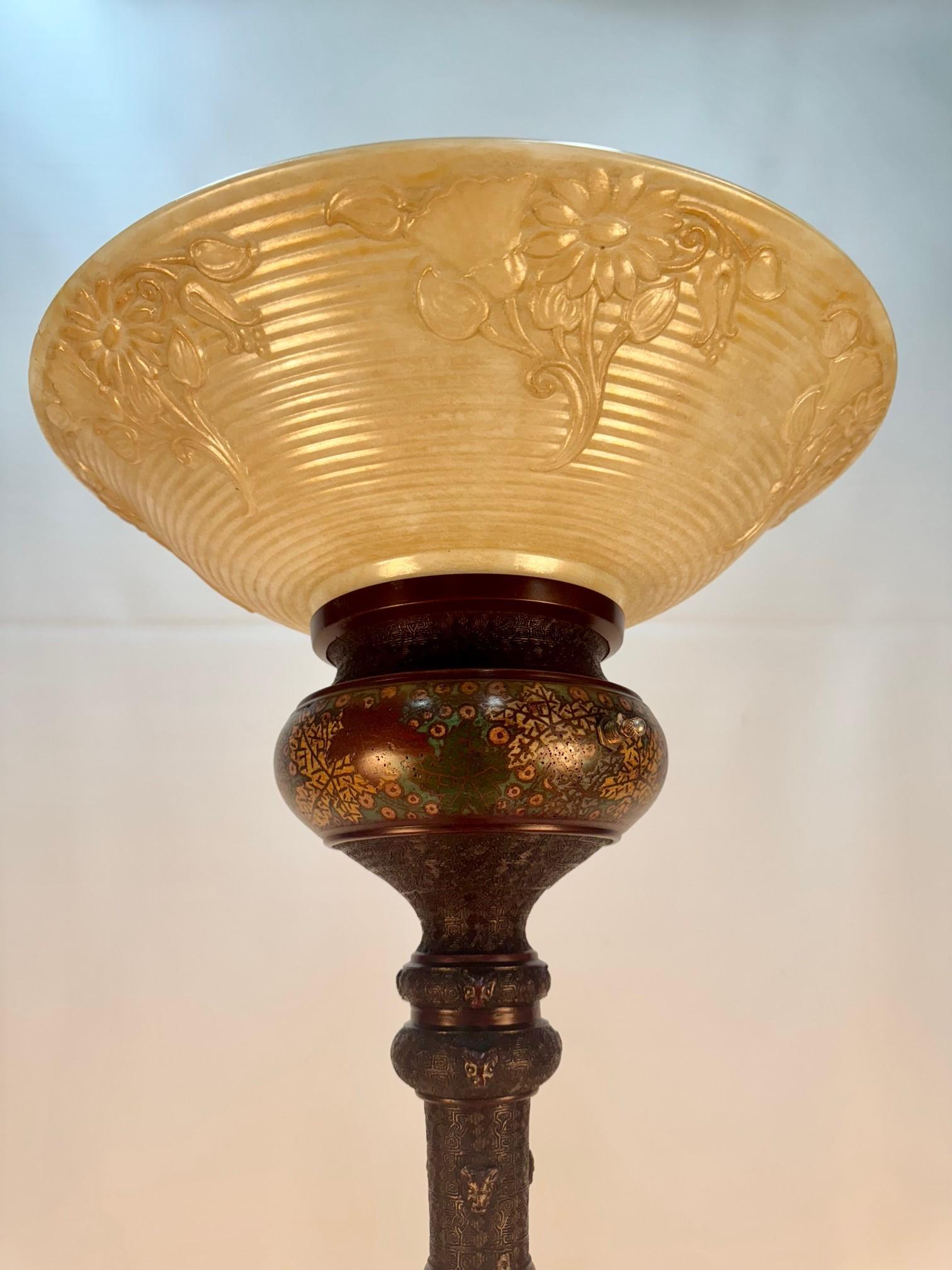 Lampada da terra giapponese, realizzata in bronzo con una patina scura e lussureggiante e decorata con smalto in tecnica champlevé con disegni floreali e contadini.  È sollevato da quattro elefanti che poggiano su un supporto a tre livelli con due
