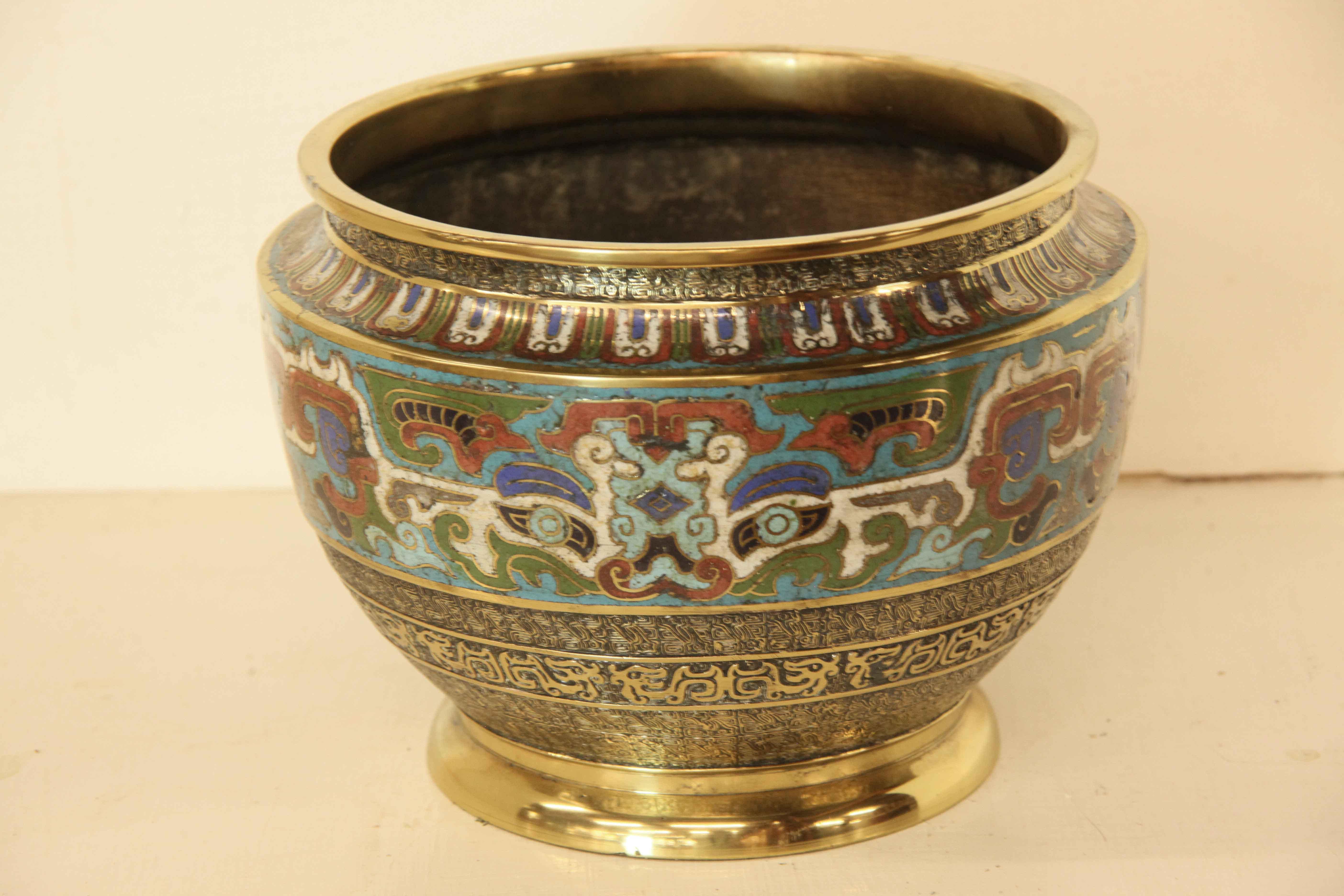 Japanese champleve cache pot,  the rim has a repetitive pattern of vertical brass with a mixture of colors (red, white, green and blue) alternating with a turquoise running below it. The main wide enamel section in the middle also features these