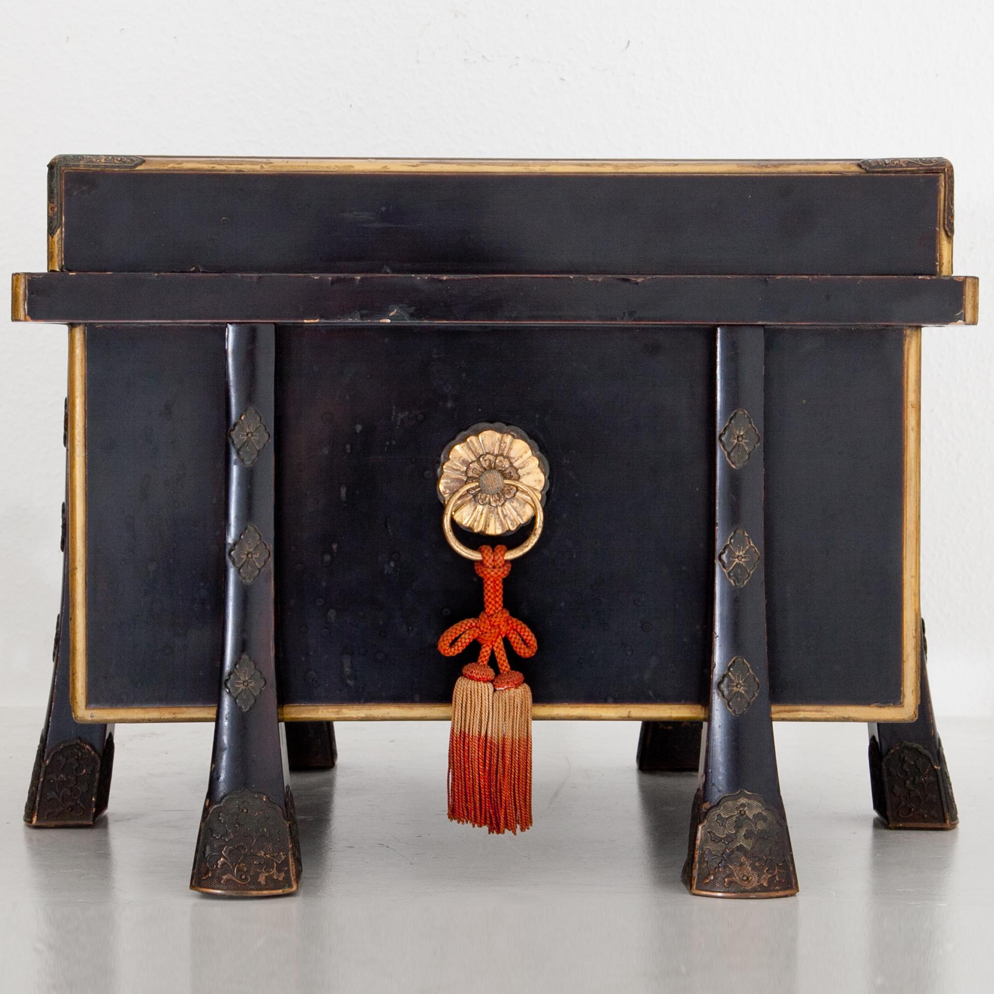 Black lacquered Japanese chest, the edges are accentuated with brass molding. The body rests on tapered legs. The lid is completely detachable. Minor losses and fading.