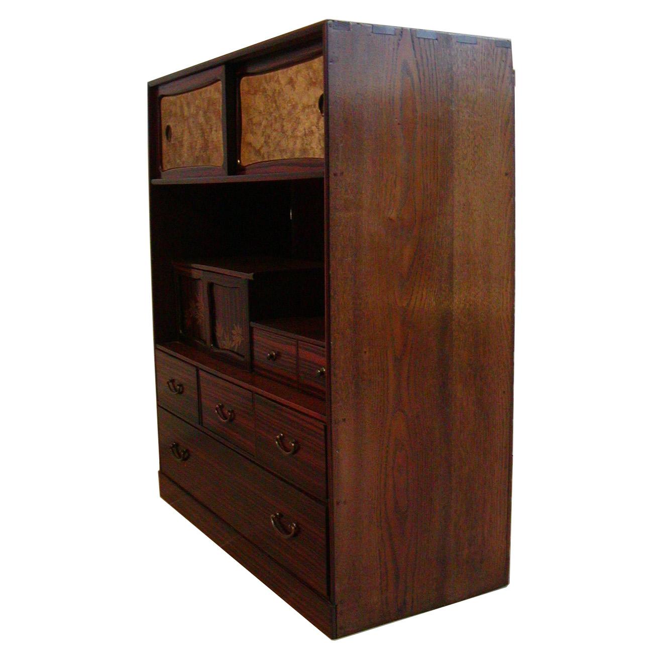 Japanese Cha-dansu (tea-chest) crafted of a chestnut casing with a rosewood veneer and Paulownia drawers, simple copper hardware with bale shaped handles, multiple small drawer and door configuration, with two sliding doors on top with inset panels
